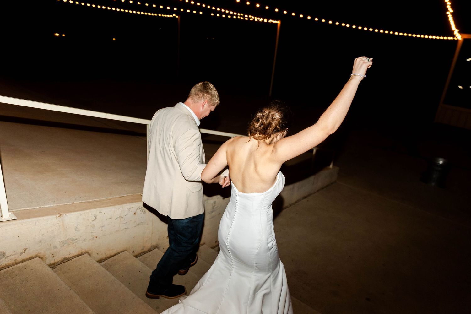 Couples dancing at a wedding reception under romantic string light decorations.