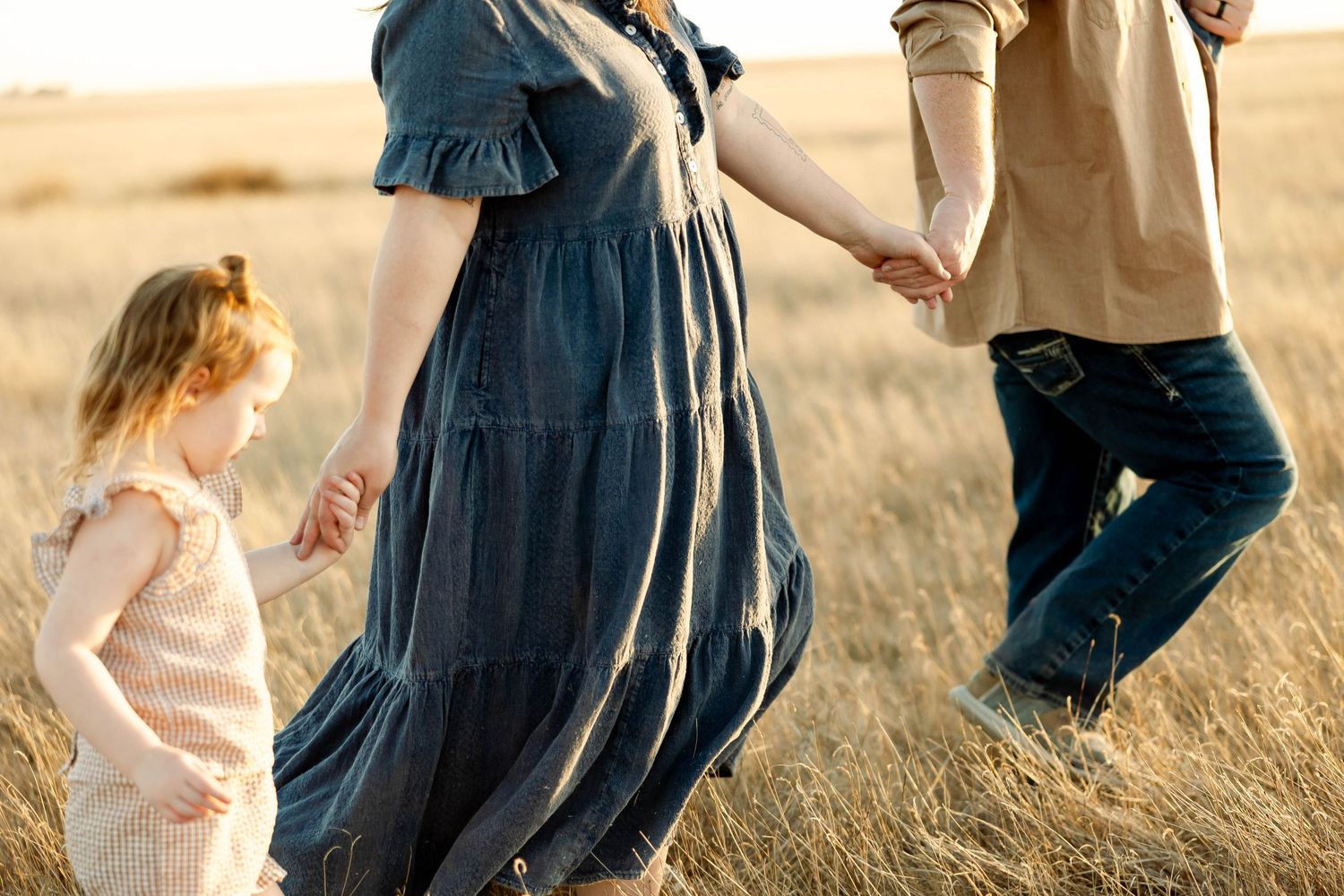 A group of people walking together through a golden wheat field at sunset.