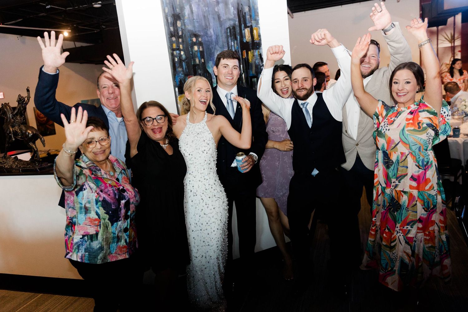 Wedding guests dancing and celebrating with raised arms on a crowded dance floor.