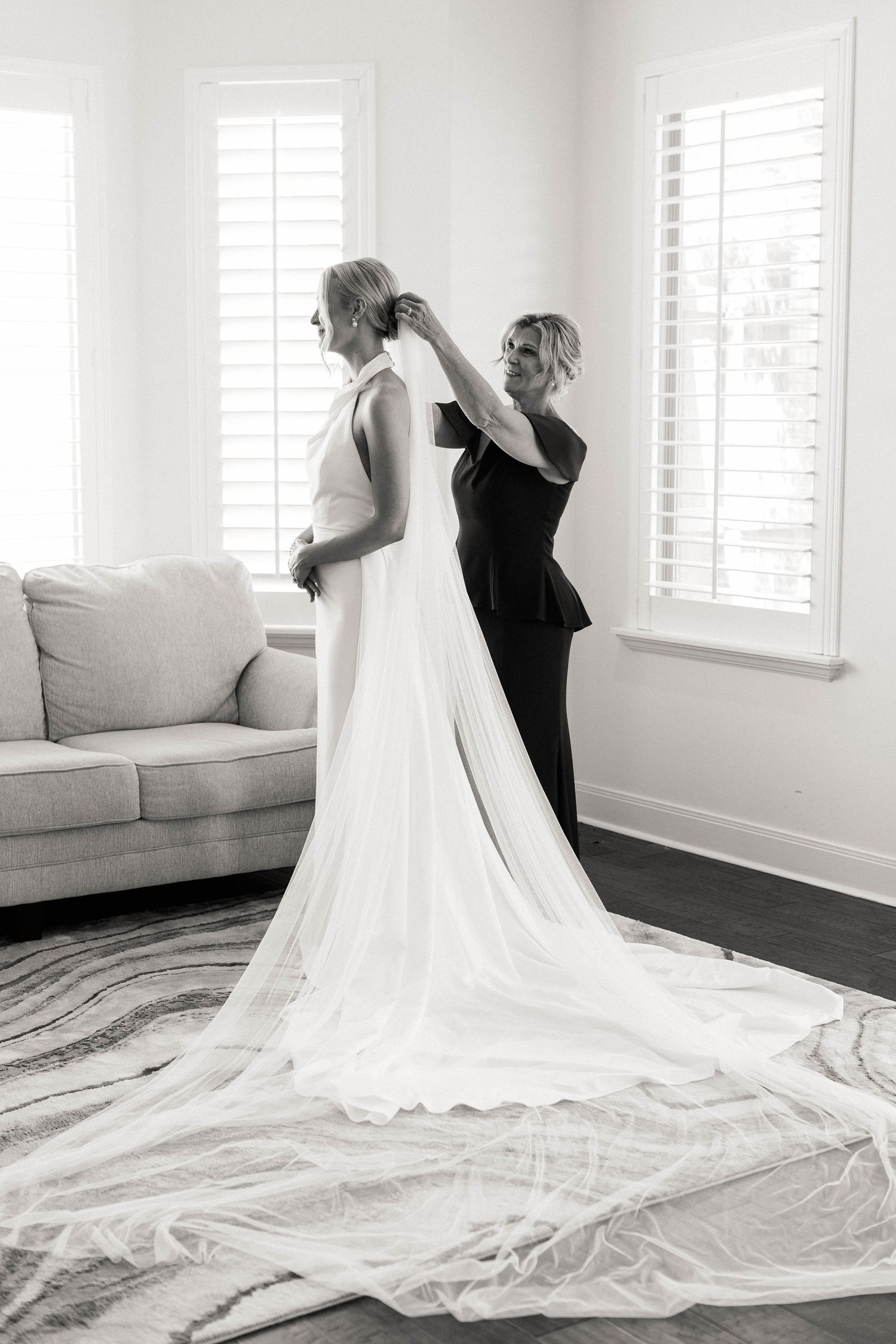 A stunning white wedding dress with long train is showcased in a bright room.