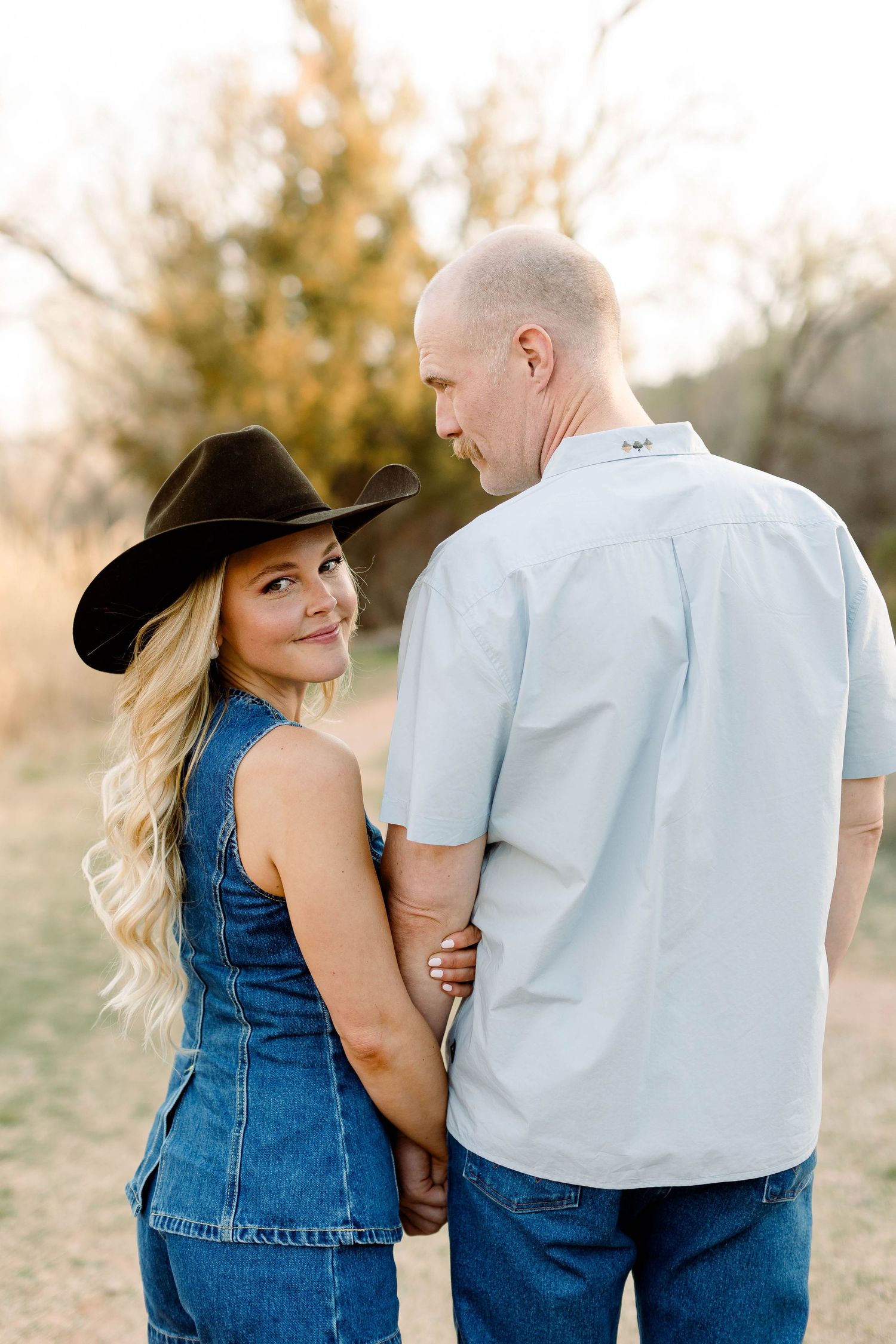 Couple in denim embracing on desert trail during golden hour photography session.