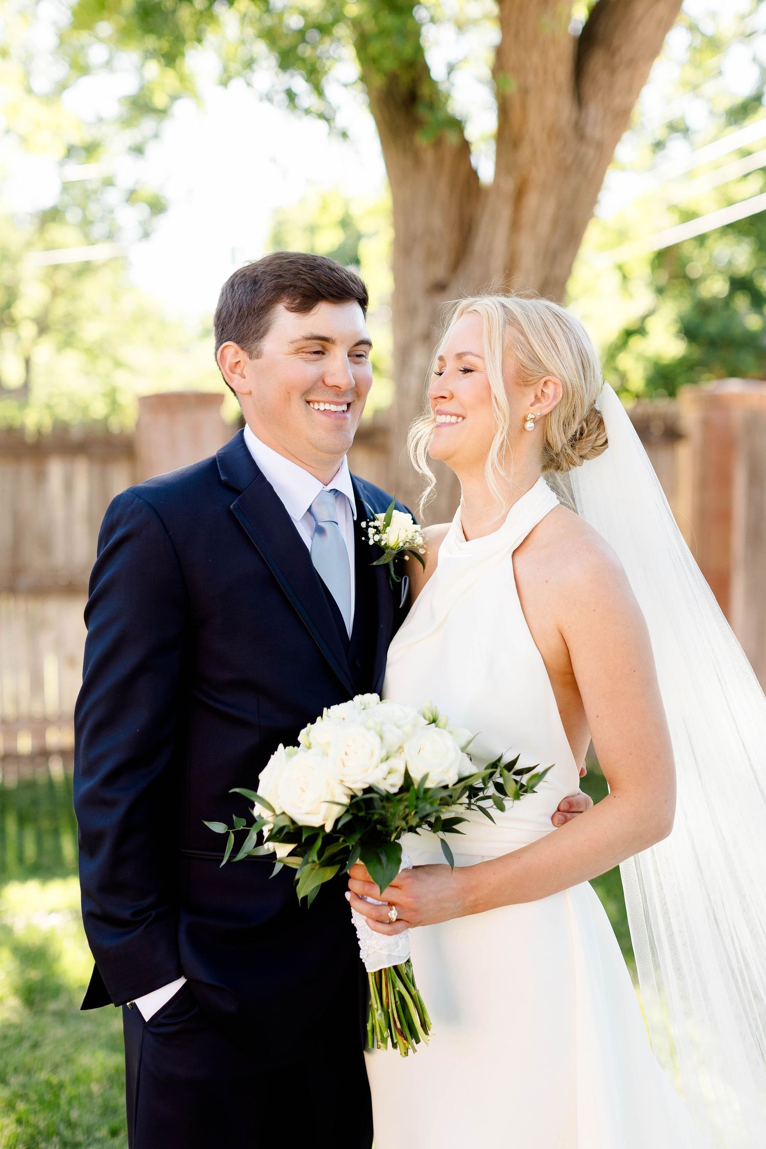 Bride and groom share joyful moments together in an outdoor garden setting.