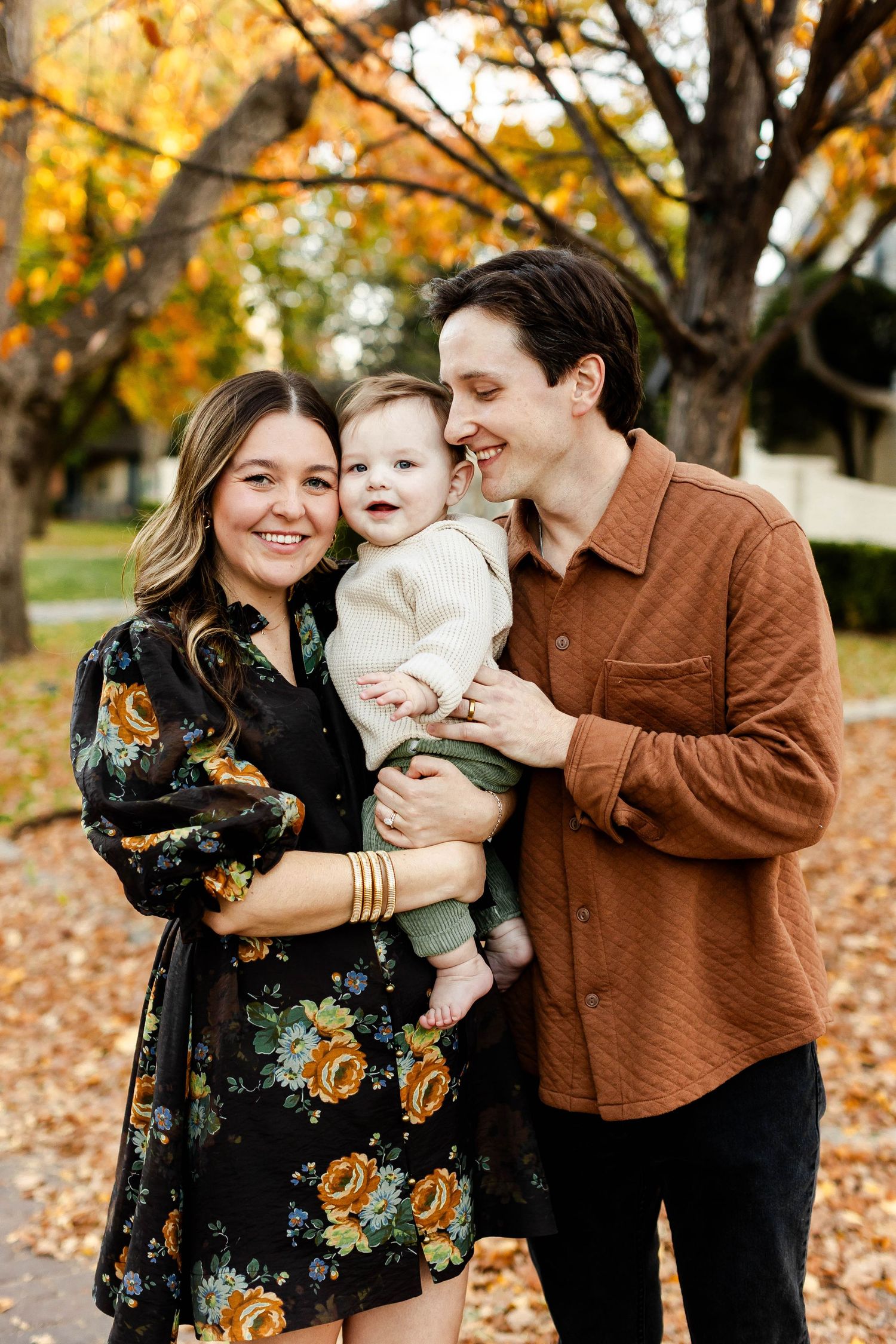 Autumn family portrait with falling leaves and warm earth tones in outdoor setting.