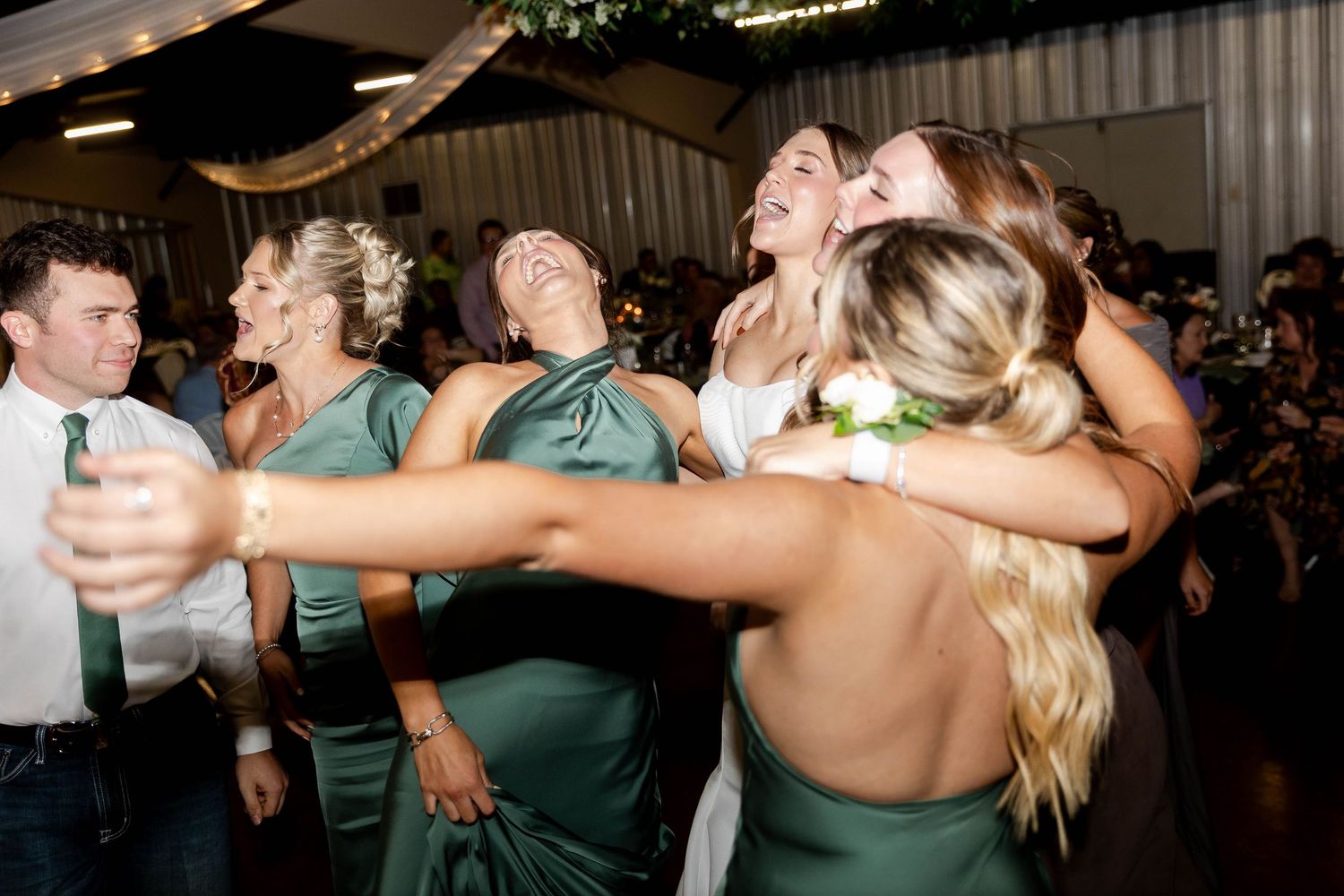 Wedding reception guests dancing and celebrating together on a dark dance floor with joyful energy.