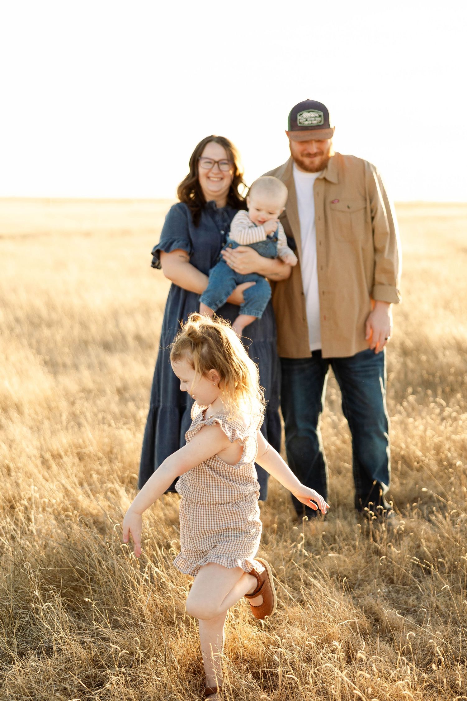 A family plays together in a golden wheat field during sunset, creating joyful moments in nature.
