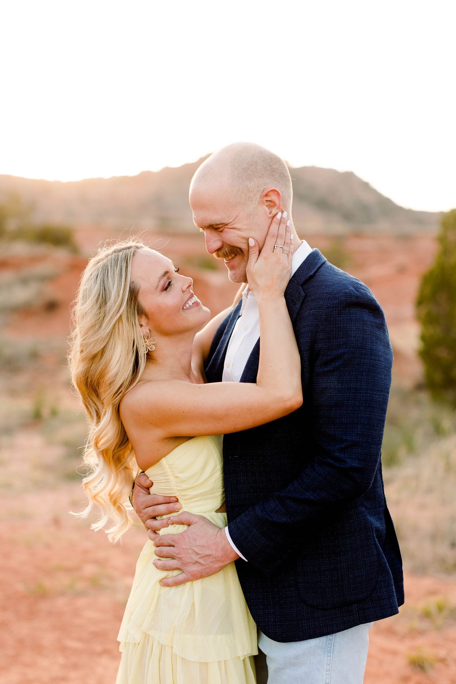 Tender moment between couple during golden hour in desert setting.