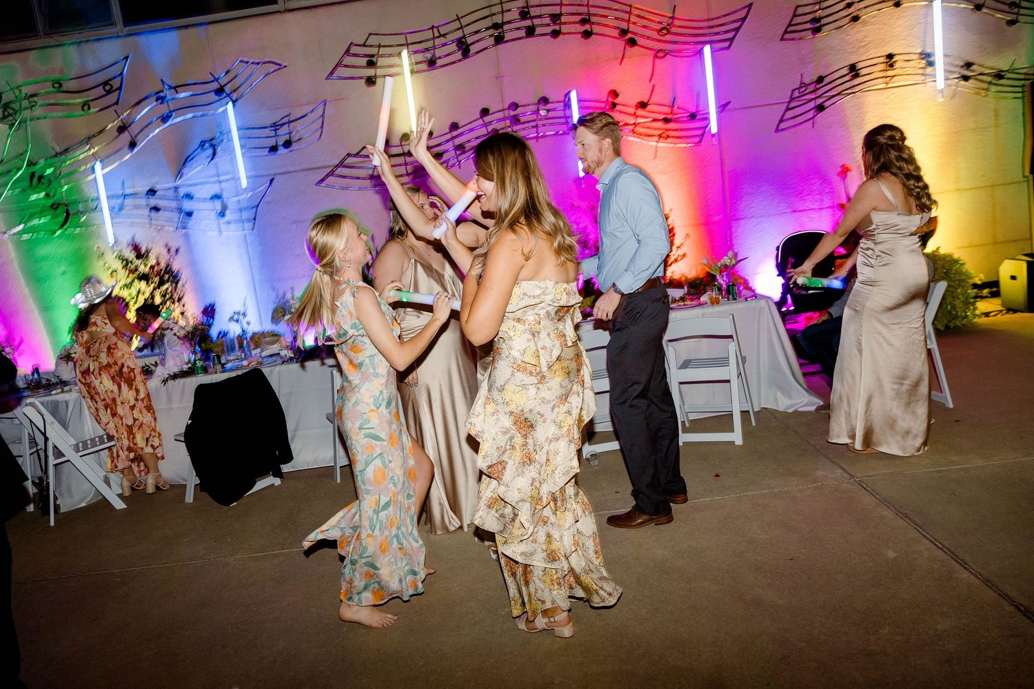 Wedding reception dance floor with colorful lighting and musical note decorations.