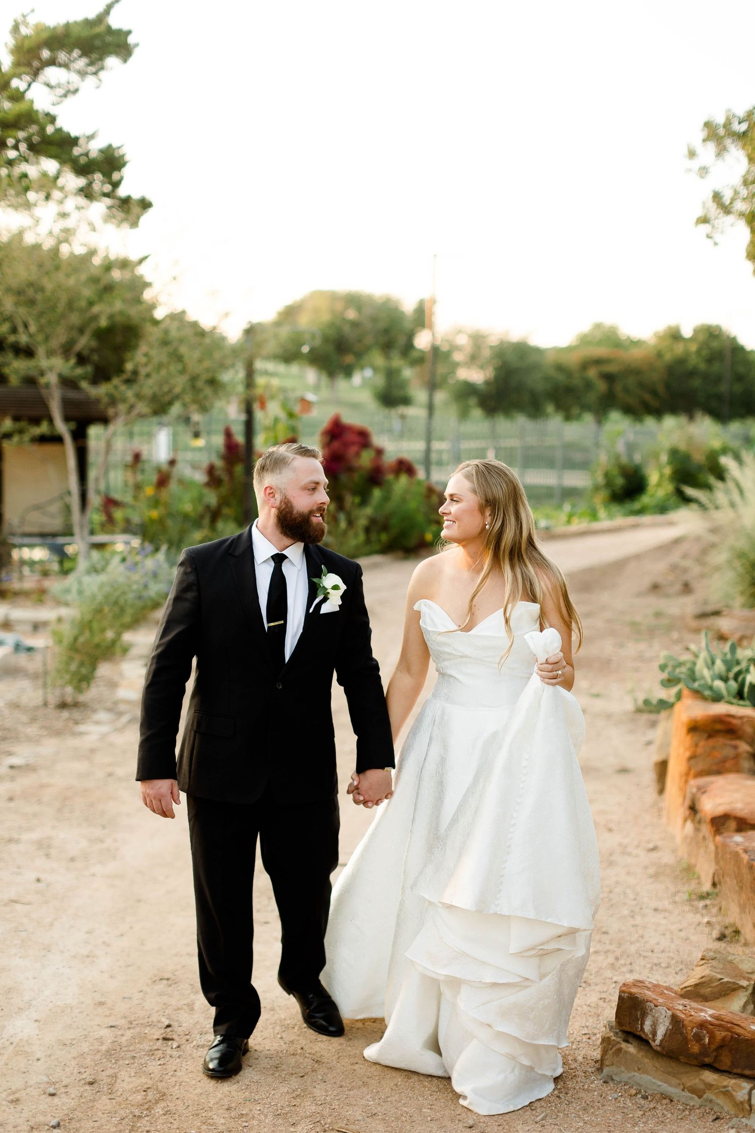 Newlyweds stroll together on rustic path during golden hour photography session.