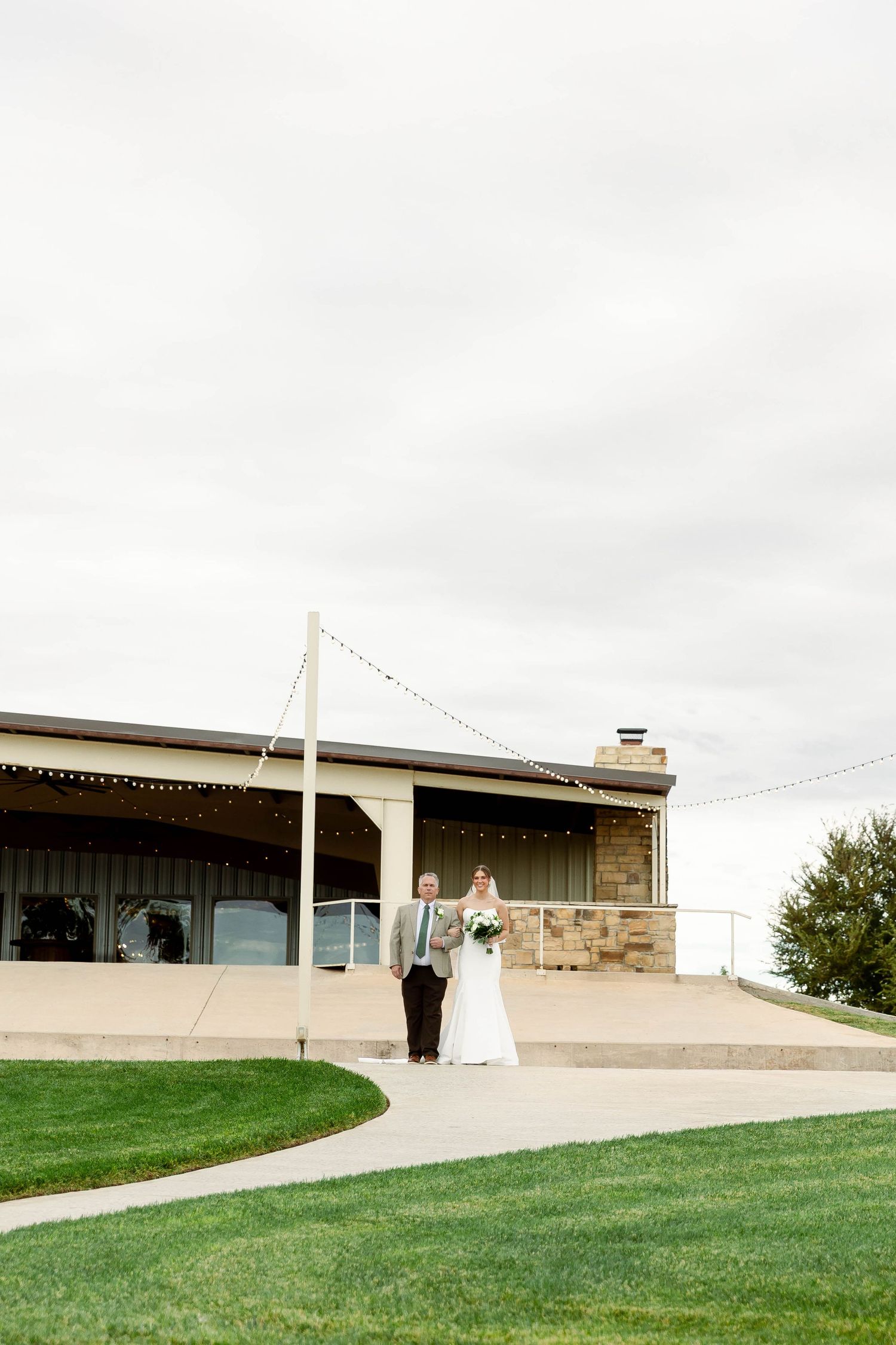 Modern wedding venue exterior featuring clean architectural lines and manicured green lawn under cloudy skies.