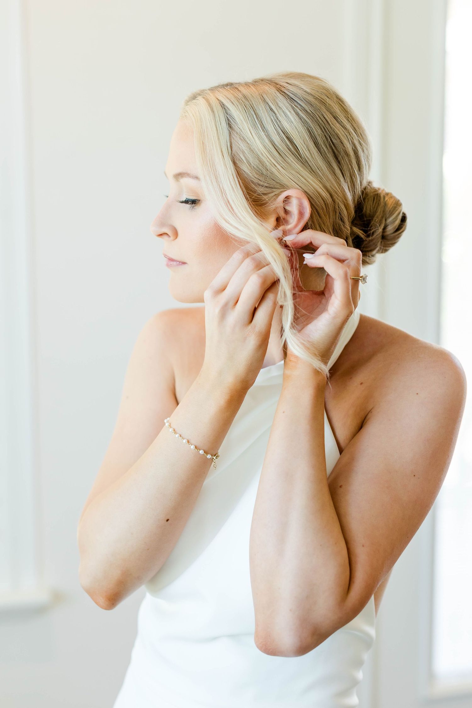 Delicate earrings being put on during wedding preparations.