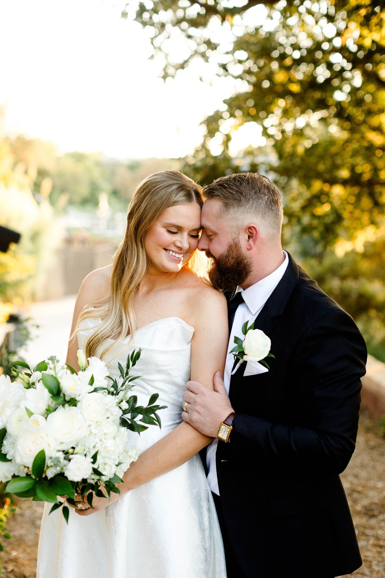 Intimate wedding portrait captured in warm sunset lighting with white floral bouquet.