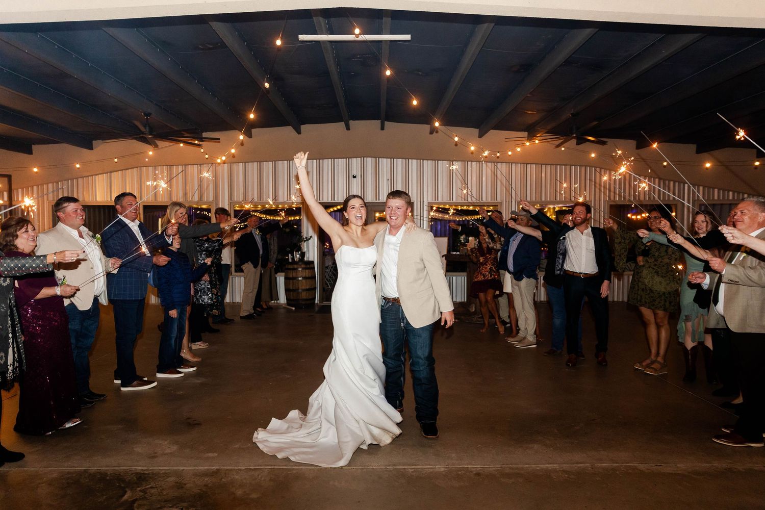 A wide view of a wedding reception dance floor with guests celebrating under tent lighting.