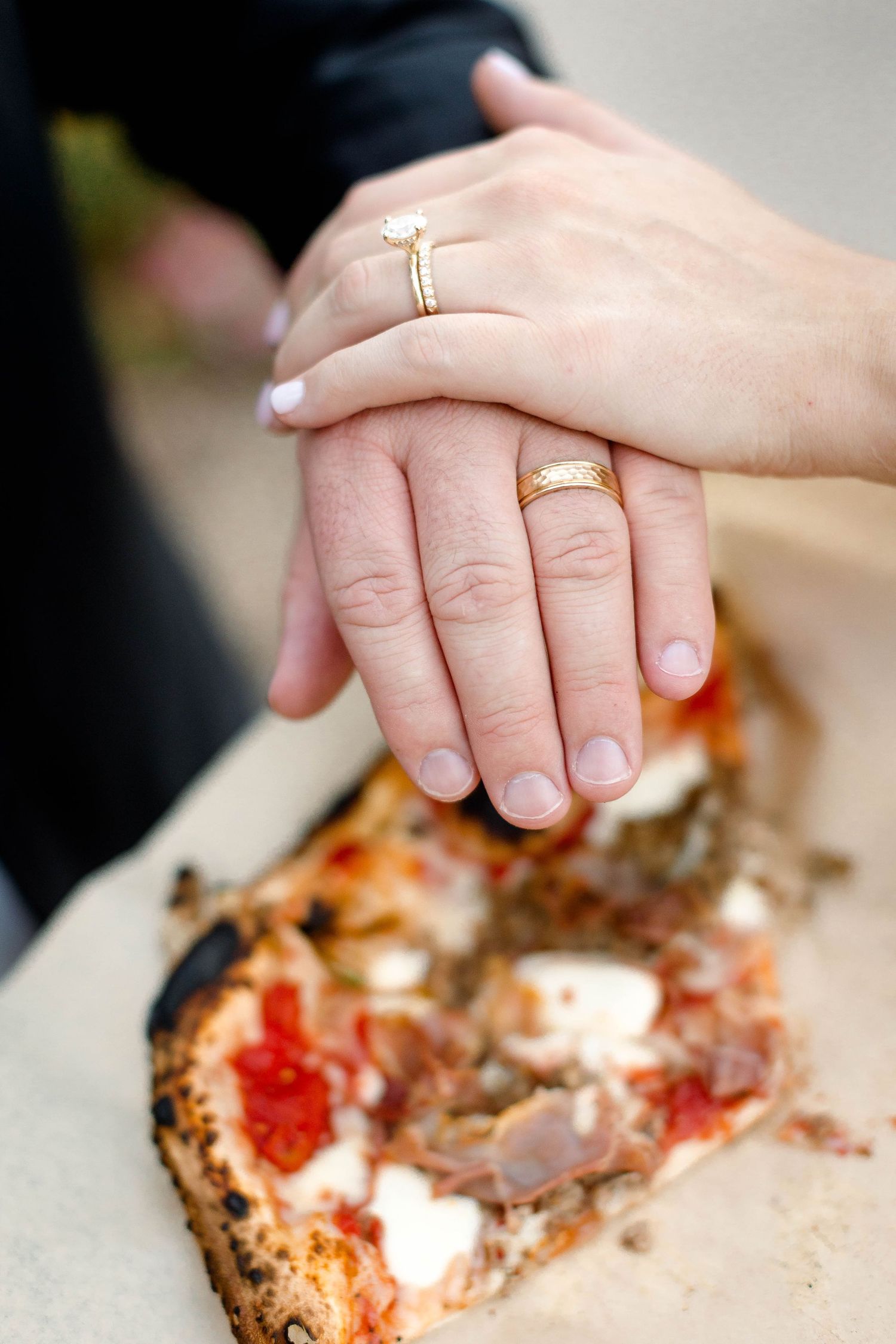 Close-up shots of hands reaching for slices of artisanal pizza on a rustic surface.