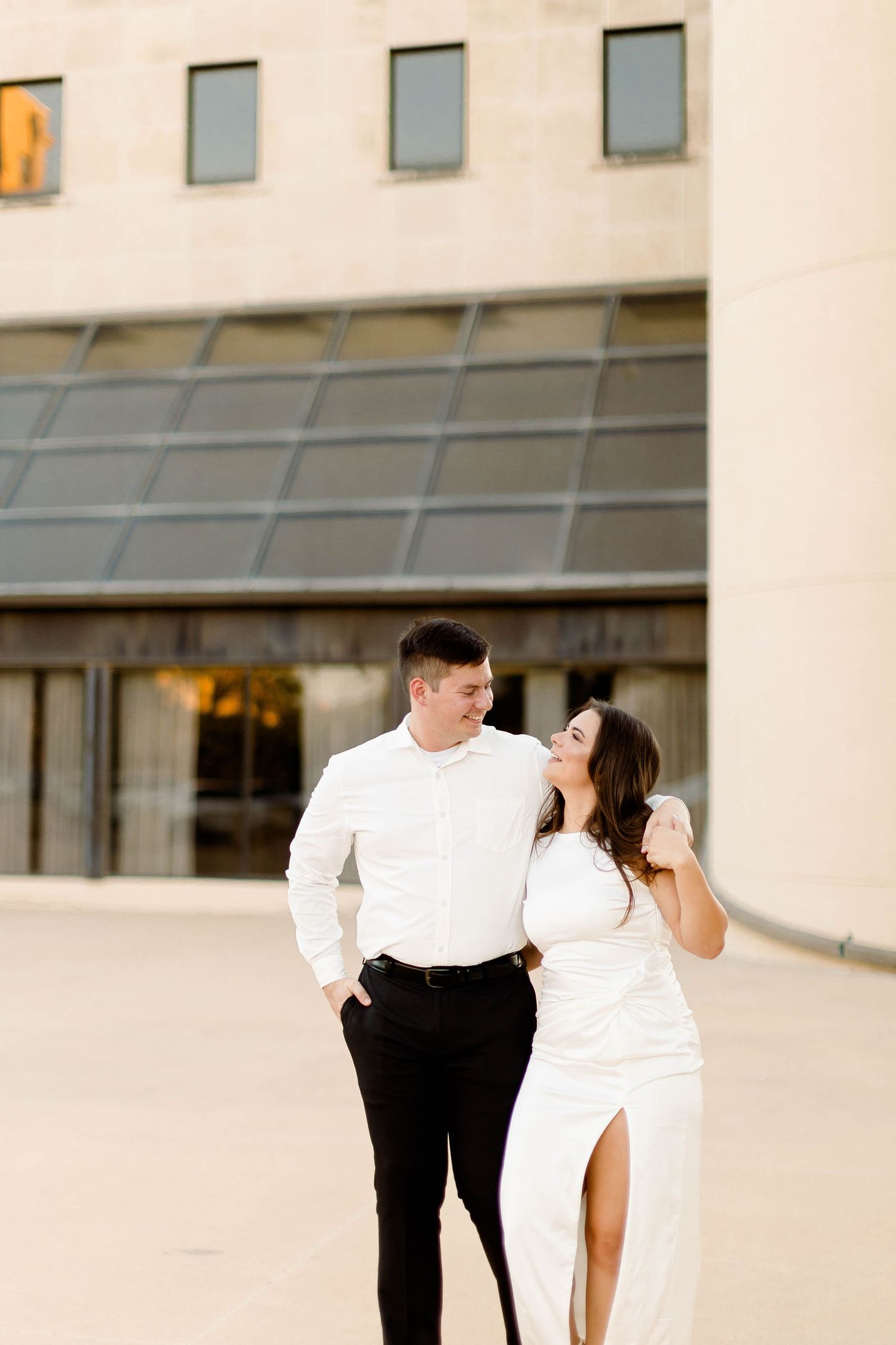 A couple dances elegantly against the backdrop of a modern building exterior.