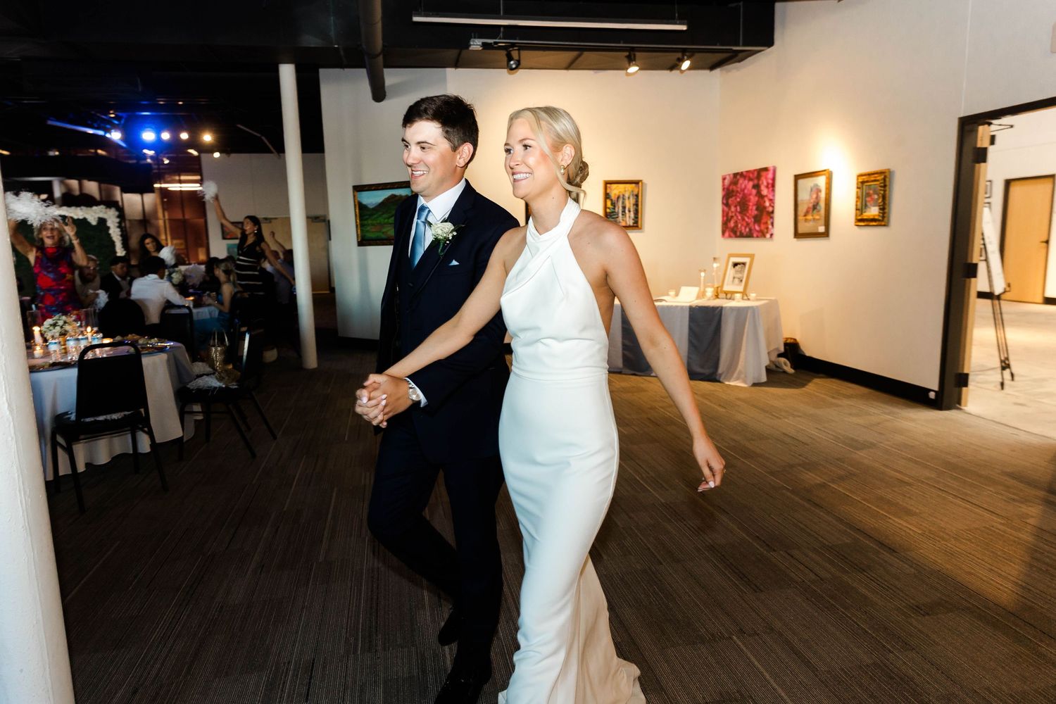 Dancers moving across a spacious gallery floor during a wedding reception.