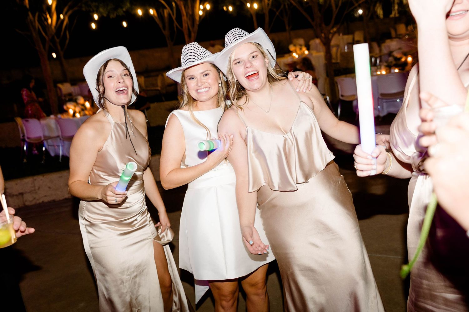 A group of people at a nighttime celebration holding drinks and smiling at a festive event.