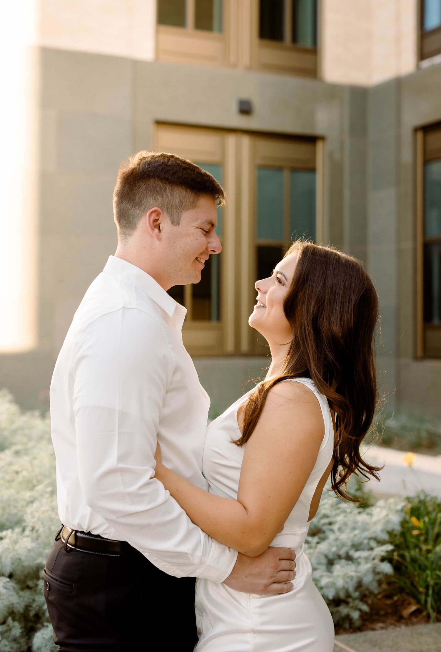 Romantic couple in coordinating outfits shares laughs during outdoor photoshoot.