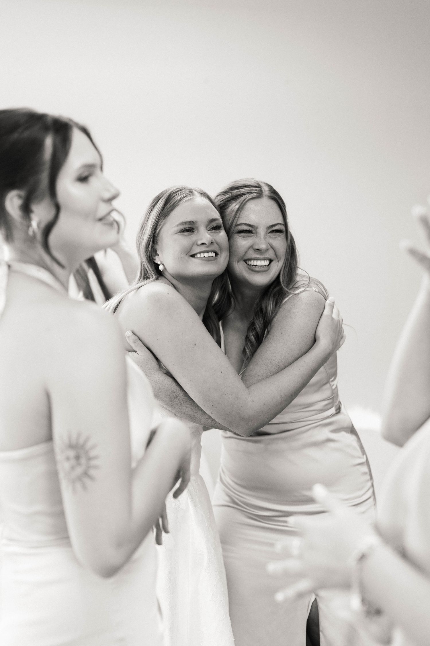 Joyful candid moments between wedding party members in white attire.