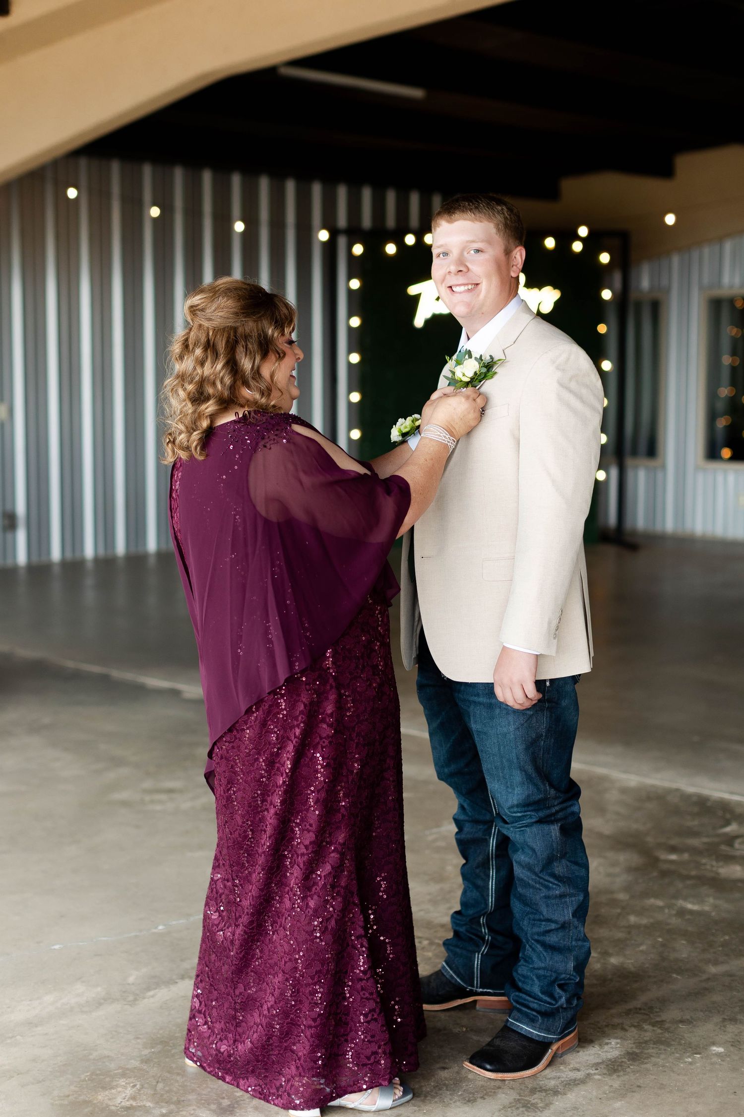 Wedding couple shares a tender moment in a rustic venue with purple and white attire.