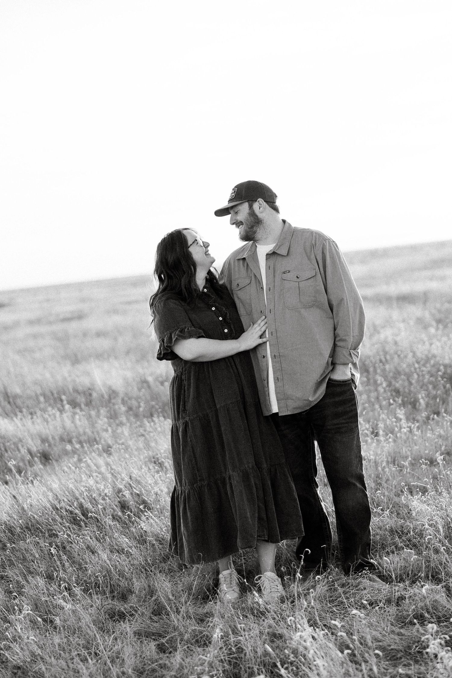 Black and white series of a couple embracing in a grassy meadow showing progressive affection and closeness.