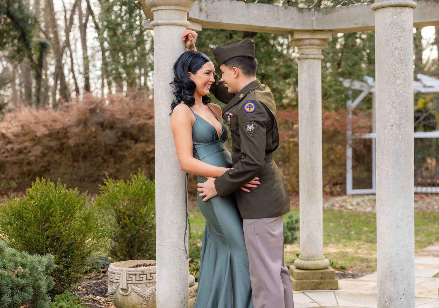 A couple embraces under an elegant columned gazebo during a romantic photoshoot.