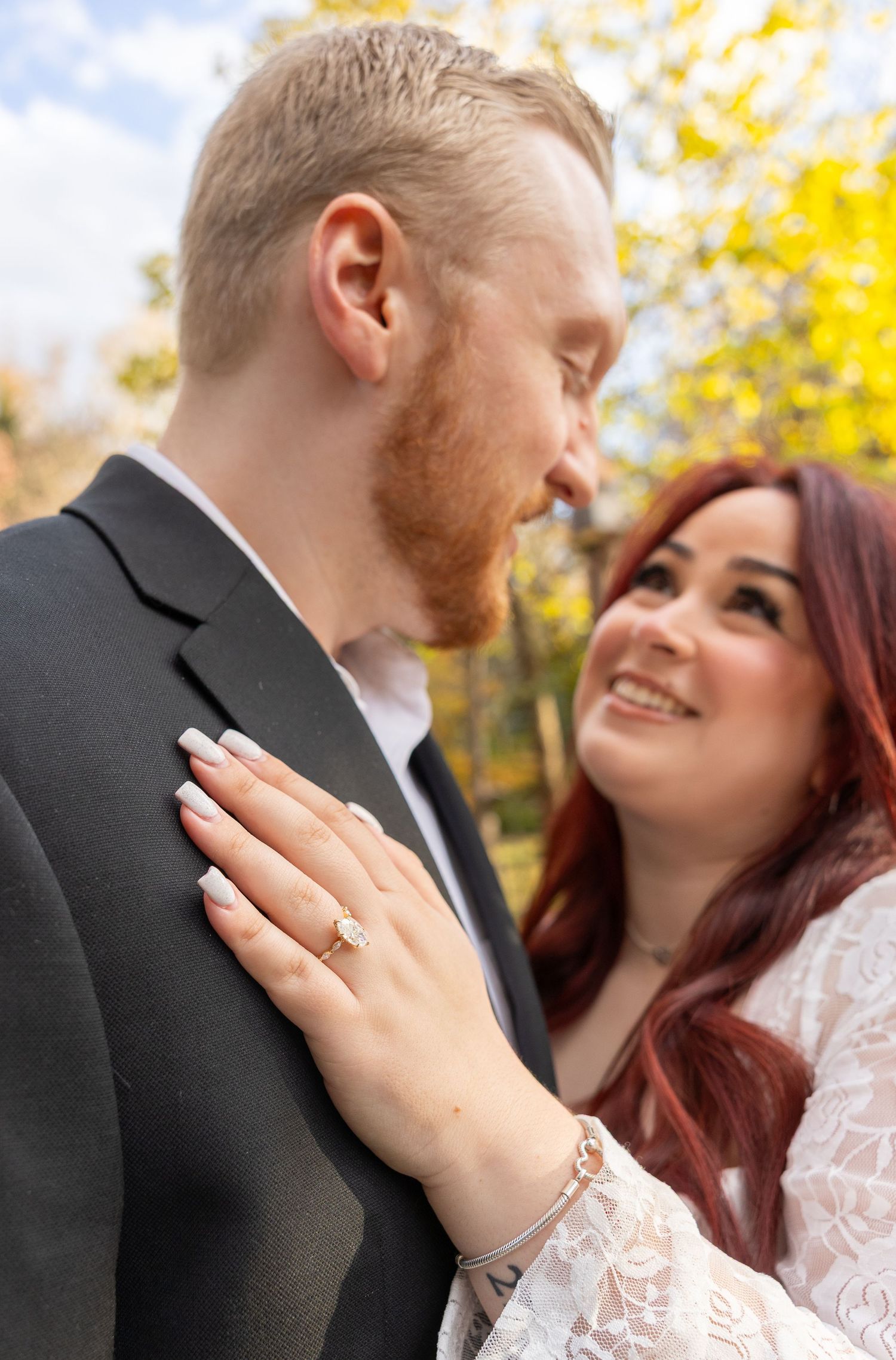 Engagement photos showing couple in formal wear with ring display in autumn setting.