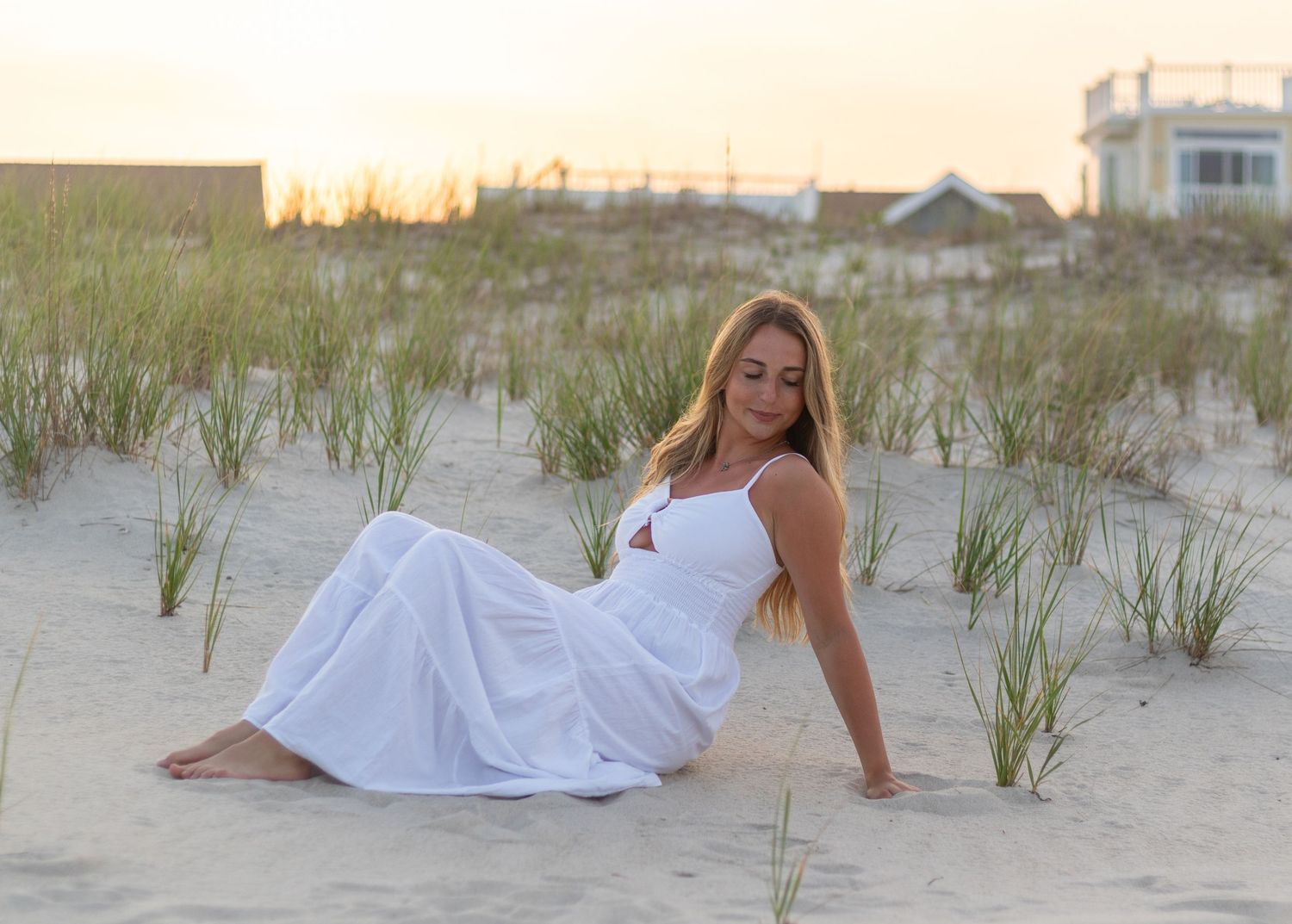Artistic beach photoshoot with sand dunes and beach grass at golden hour.