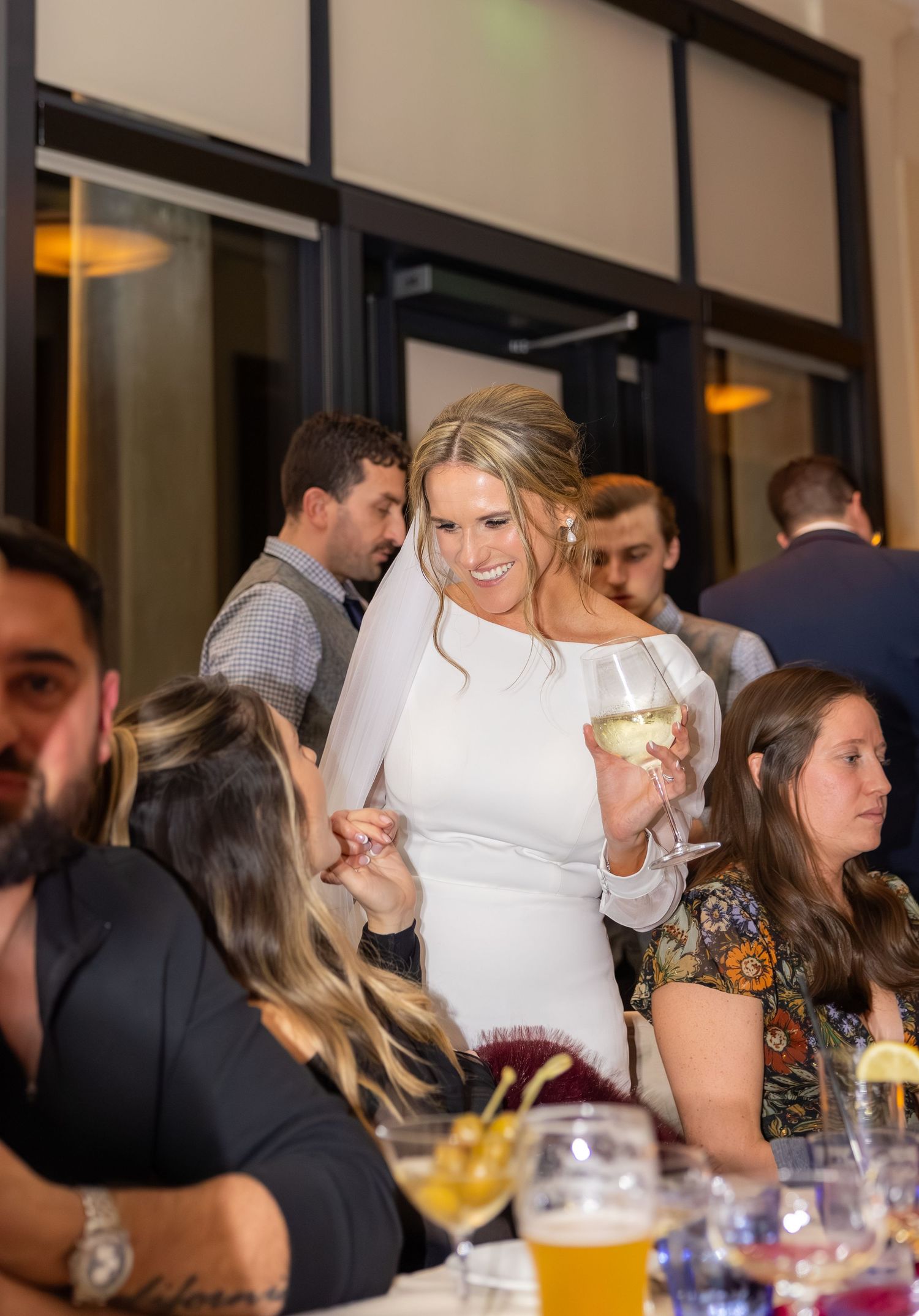 Wedding reception guests enjoying drinks and conversation at a lively indoor celebration.