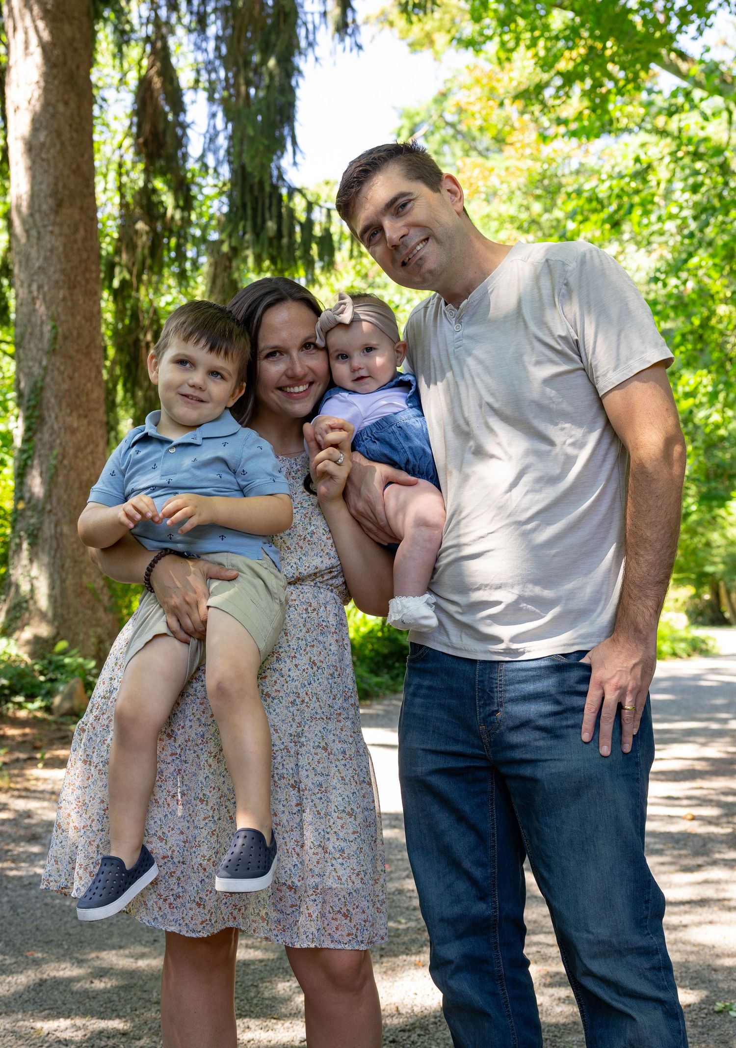 Family portrait series under green trees in a park setting.