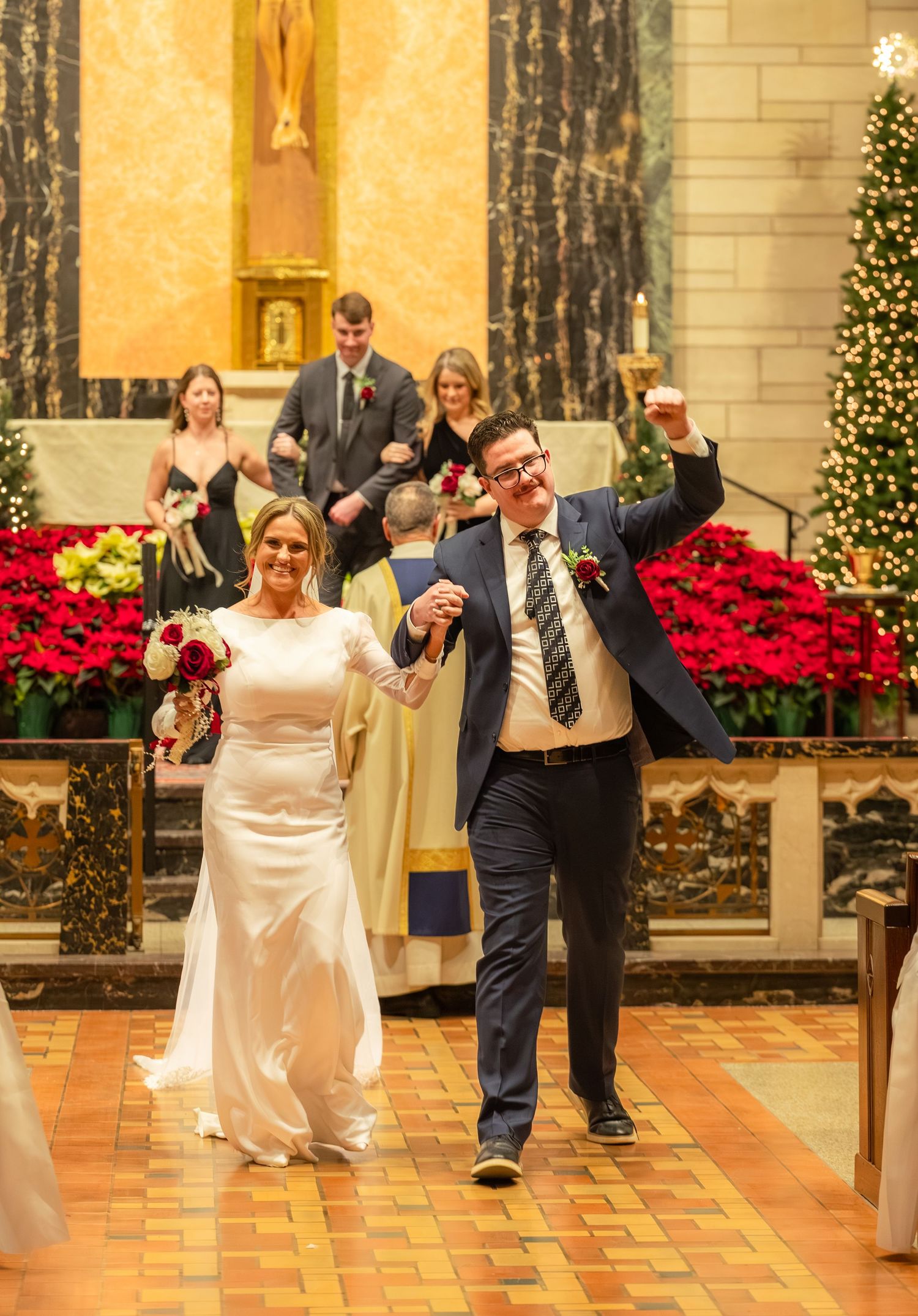 Newlyweds celebrating with joyful dance moves in an ornately decorated venue with poinsettias.