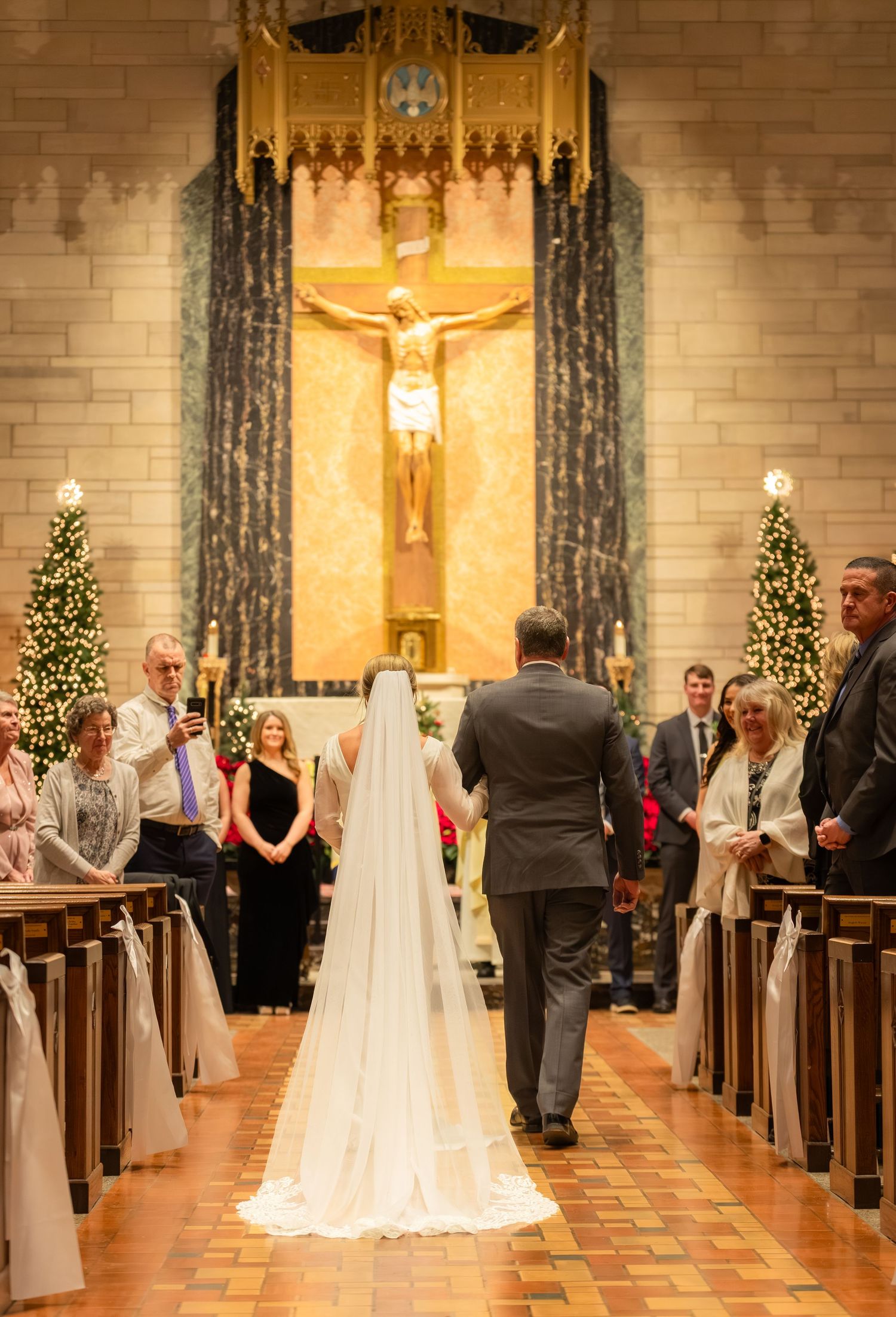 Church wedding ceremony with guests seated in pews and decorated altar.