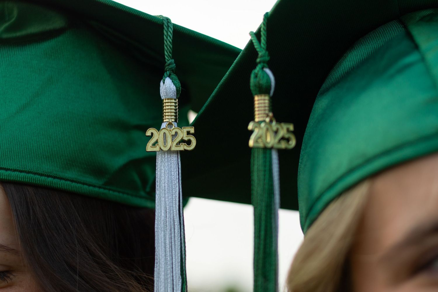 Green graduation caps with 2025 tassels shown in close-up detail.