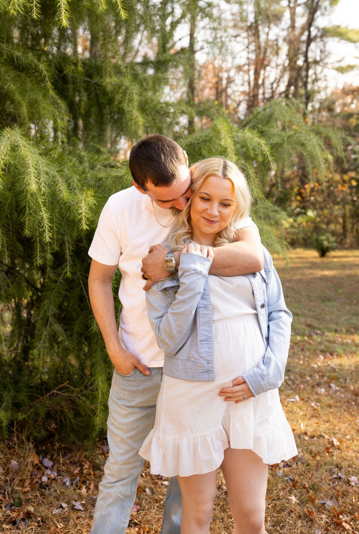 A couple shares sweet moments together in a wooded outdoor setting.