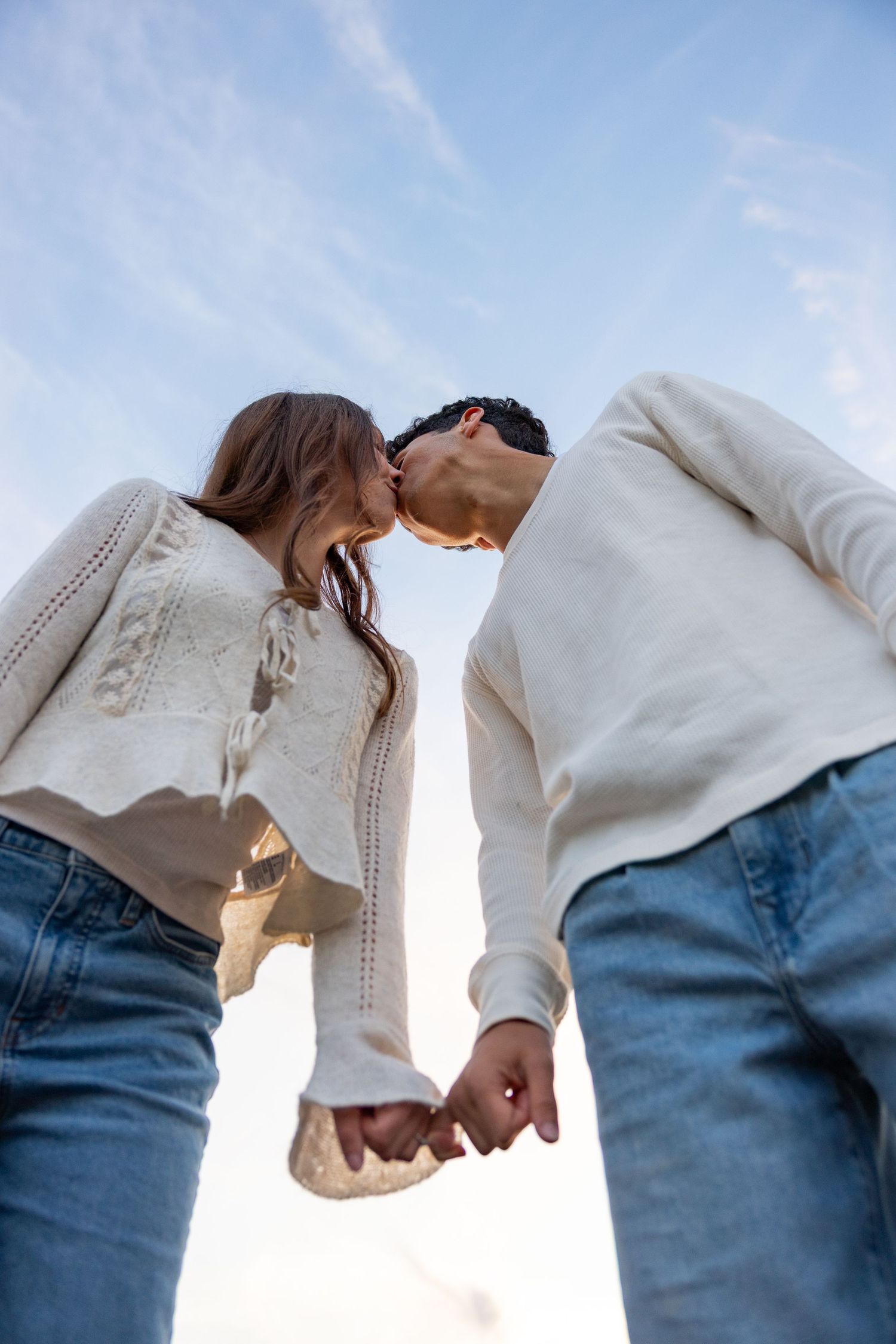 Artistic sequence showing two people holding hands against bright sky background.