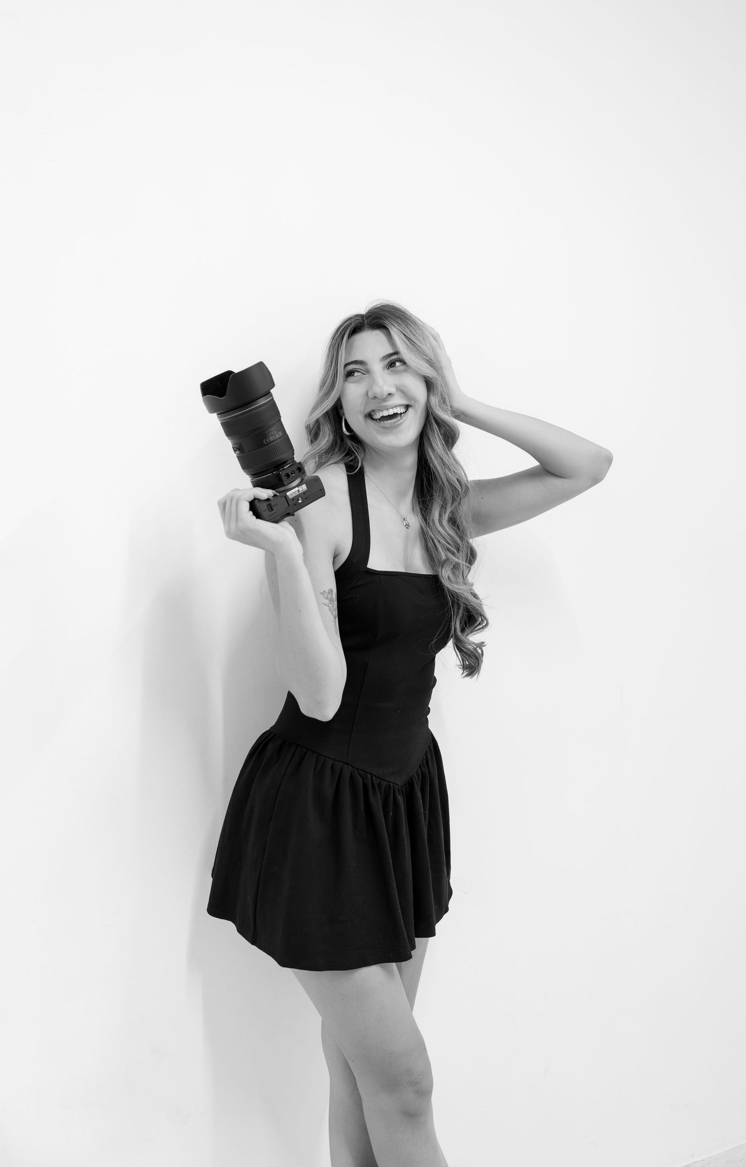 Black and white portraits of a photographer posing playfully with her camera equipment.
