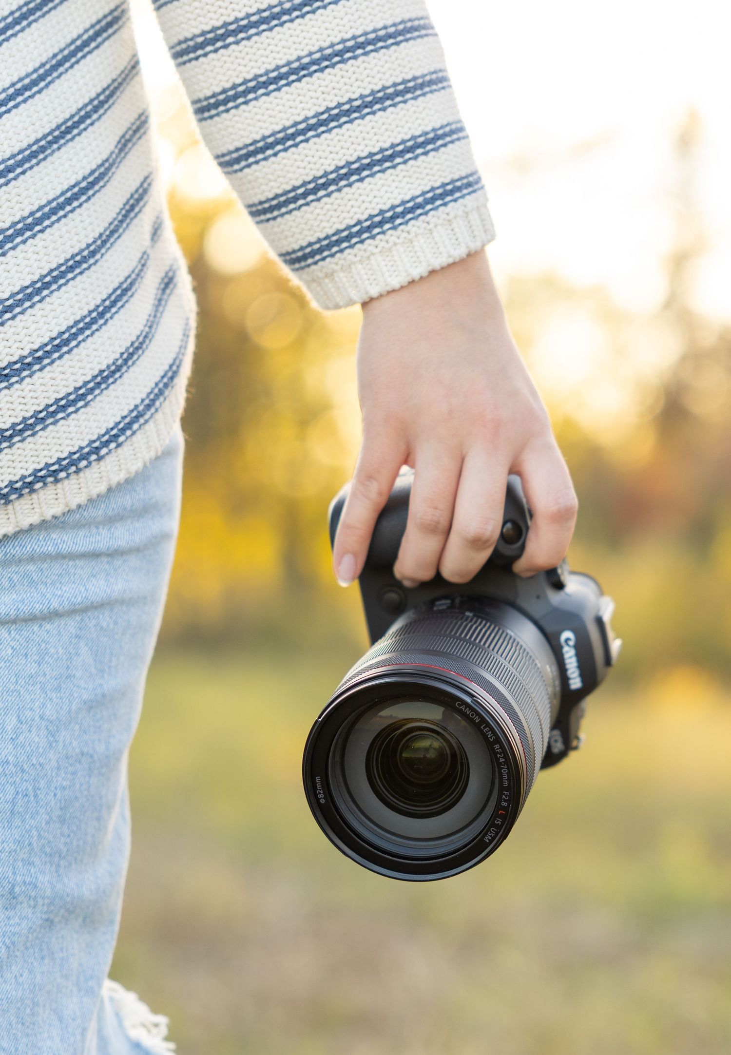 Close-up shots of hands holding a professional camera lens in natural outdoor lighting.