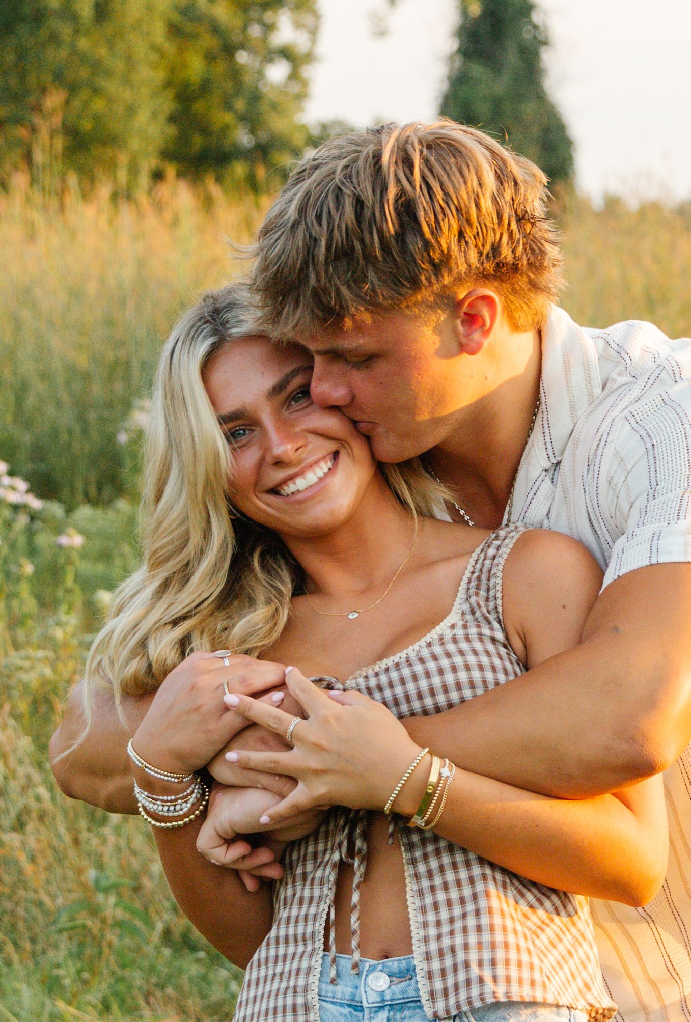 Playful couple embracing in a wildflower field at sunset.