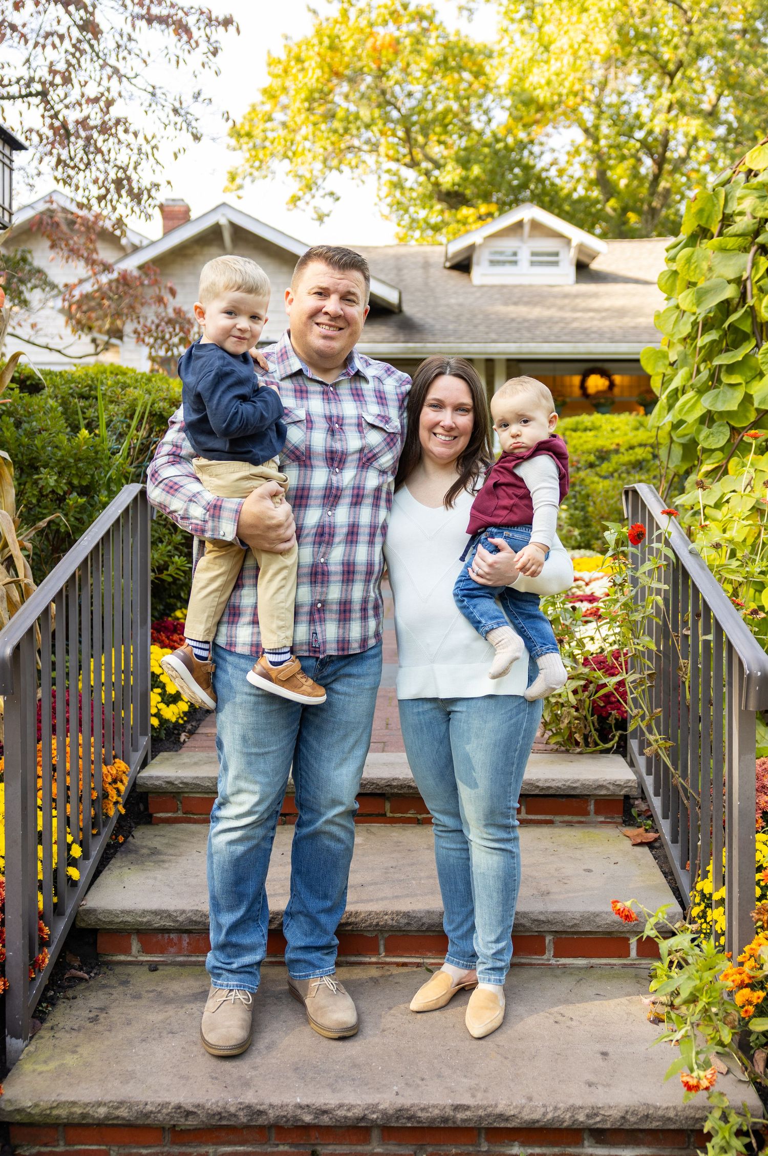 Family portrait series on wooden deck with autumn foliage in background.