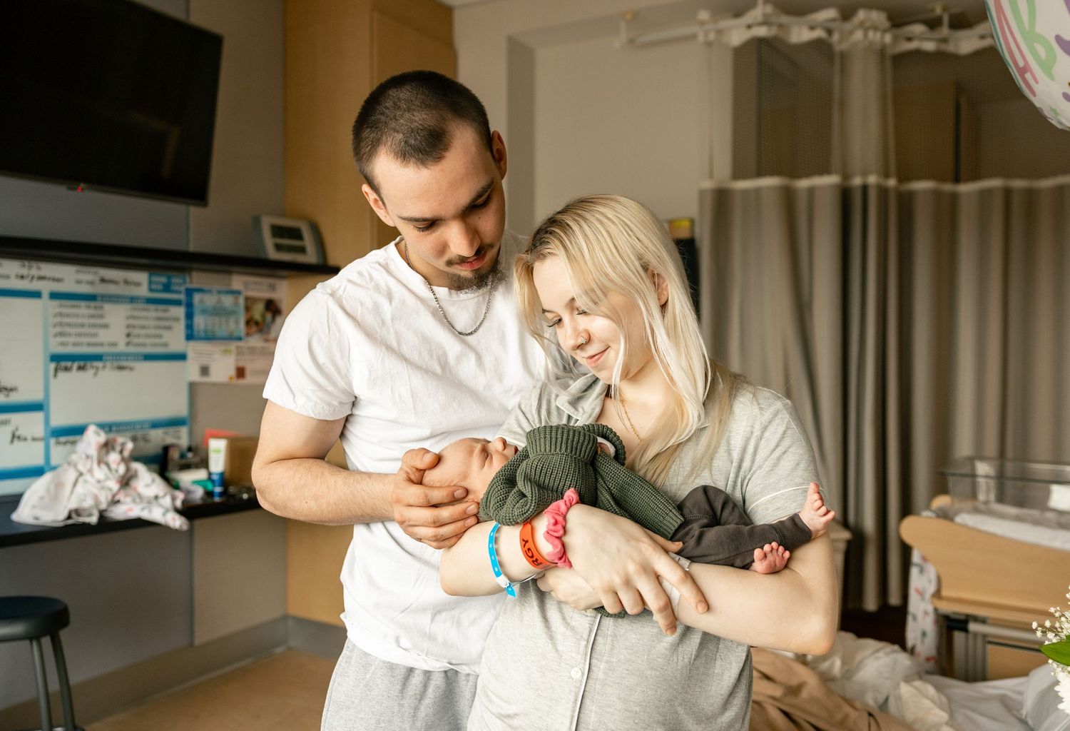 Medical professional in white coat examines newborn baby in hospital setting.