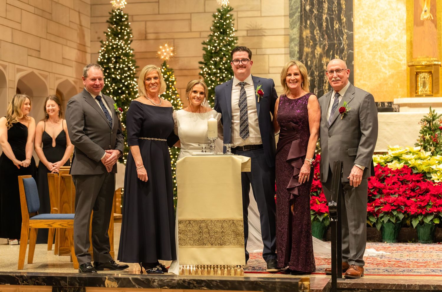 Church wedding ceremony with holiday decorations and poinsettias along the aisle.