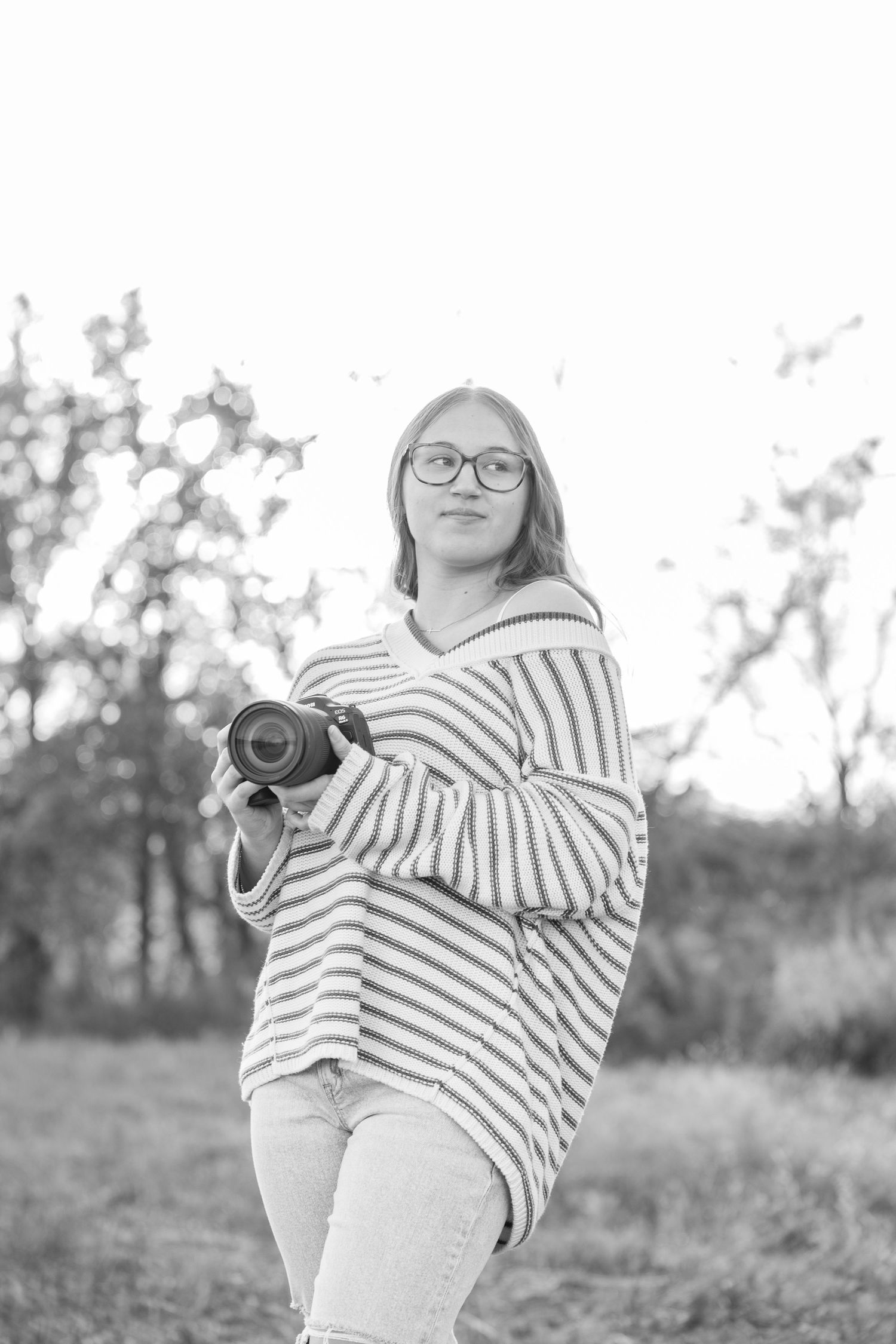 Someone wearing glasses and striped clothing poses casually outdoors.