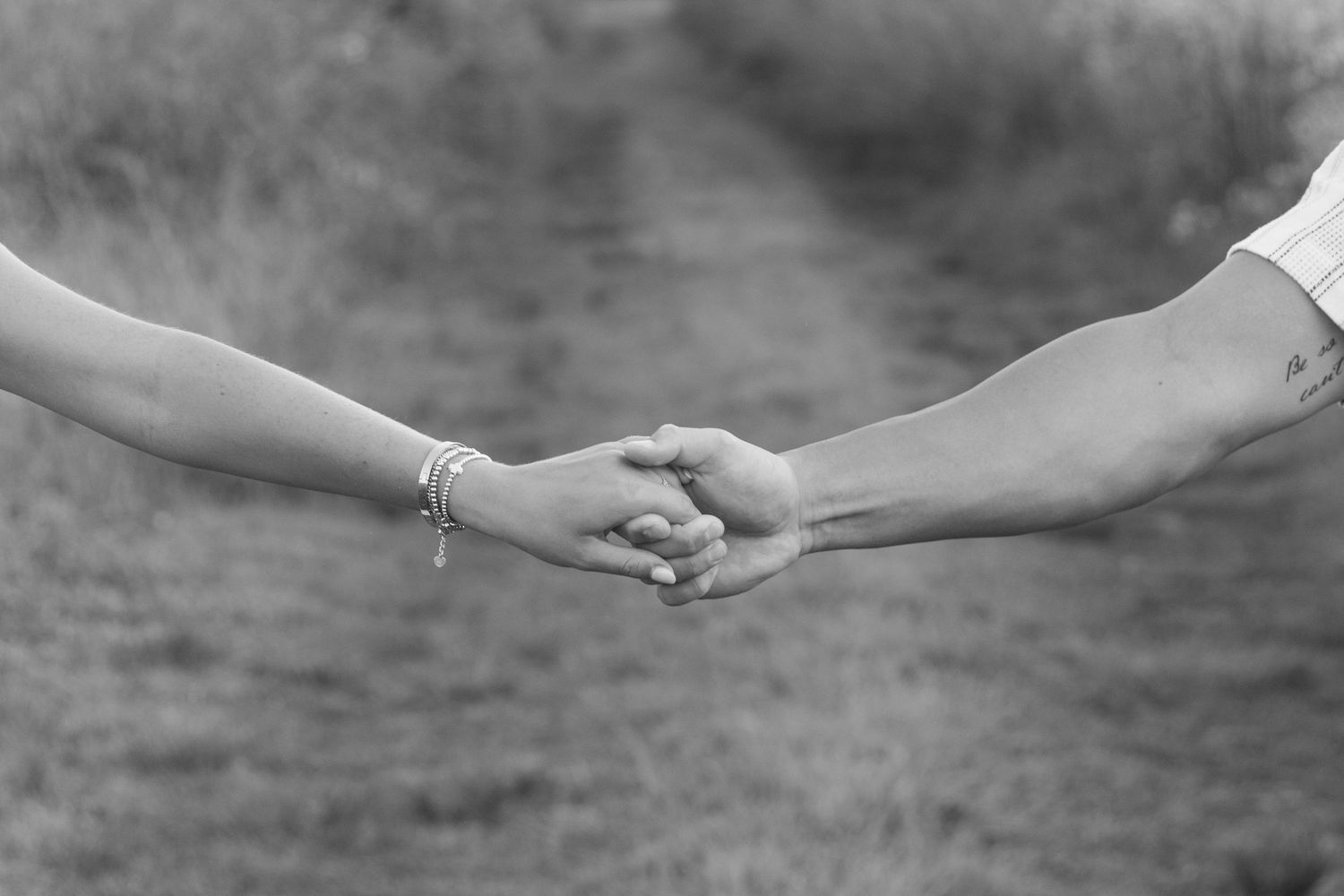 Close-up shot of hands reaching towards each other in black and white.