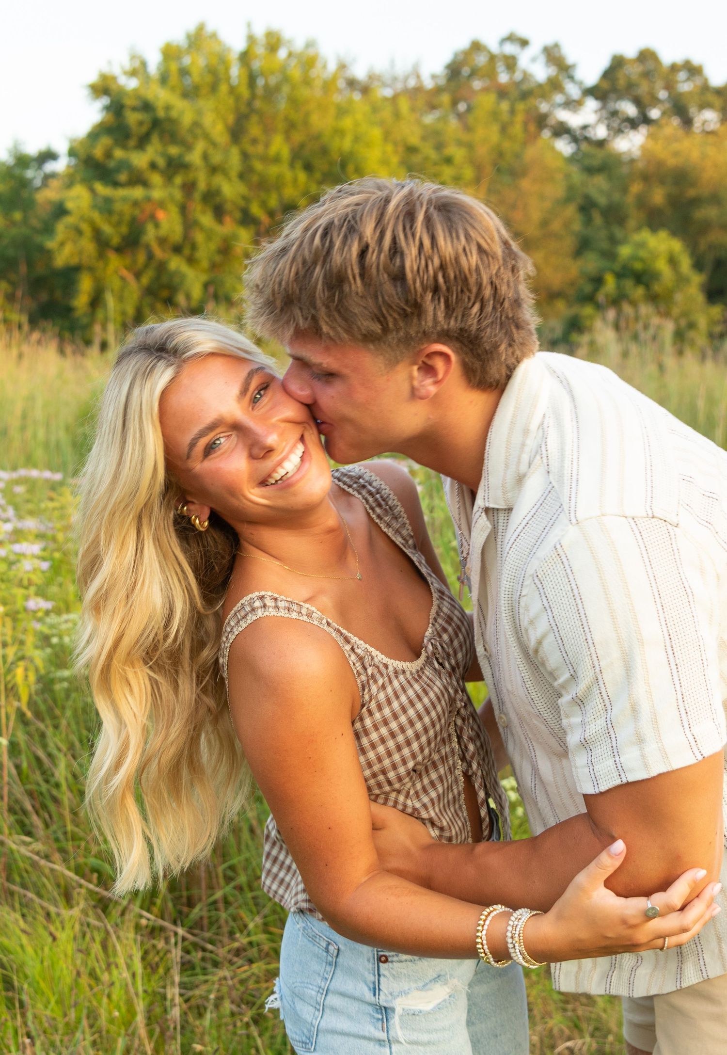 Romantic couple sharing intimate moments in a summer meadow during golden hour.