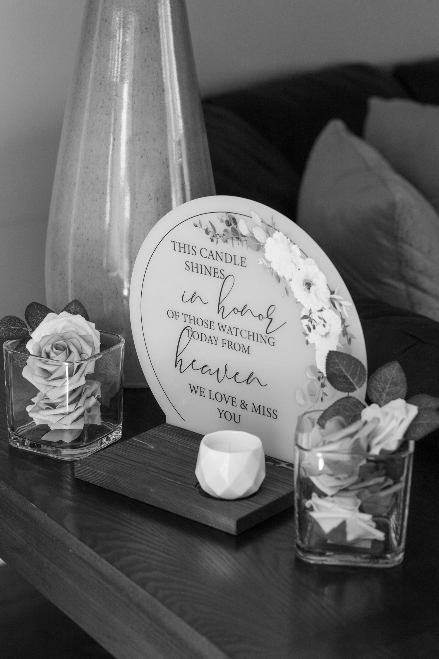 Black and white image of decorative candles and roses with text cards on a wooden surface.