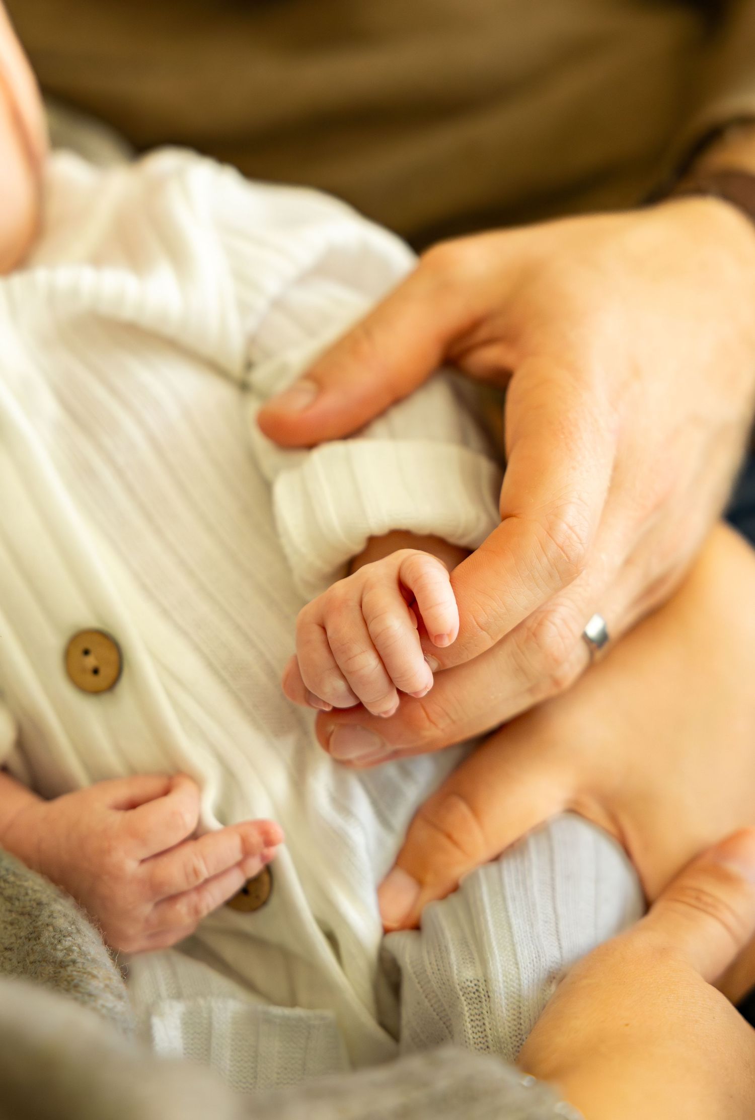 Gentle close-up of newborn baby's hands being held by parents.