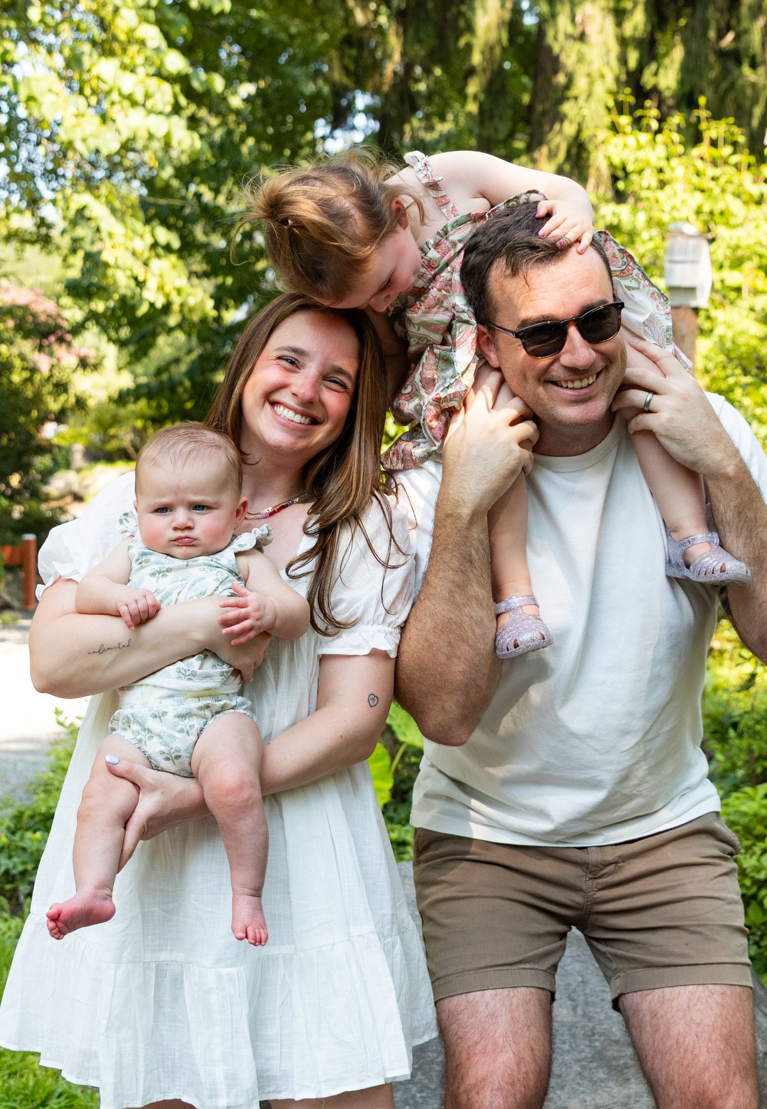 Family shares joyful moments together in a sunny garden setting wearing coordinated white outfits.