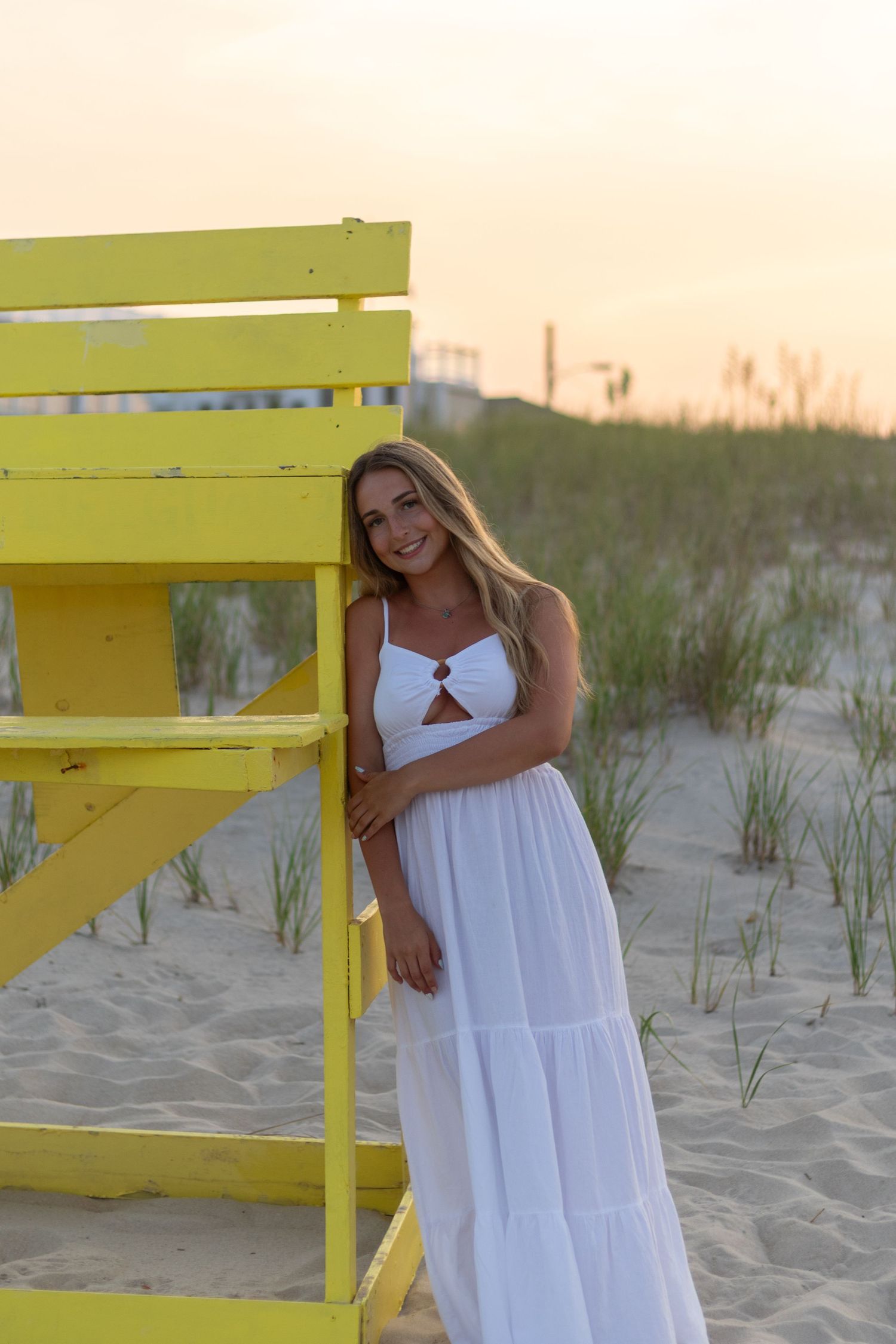 A series of beach photos featuring a yellow lifeguard stand and white dress against sandy dunes at sunset.