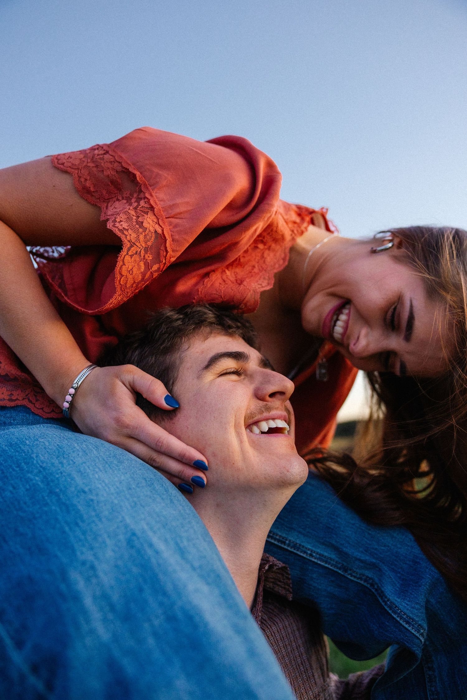 Intimate couple laughing together during outdoor sunset photoshoot.