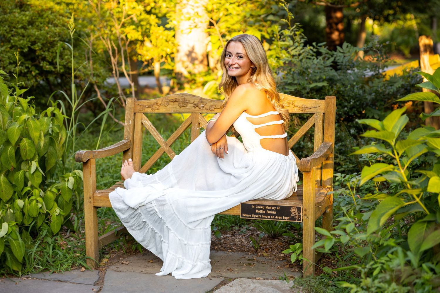 Outdoor portrait in a garden setting with golden sunlight and white dress.