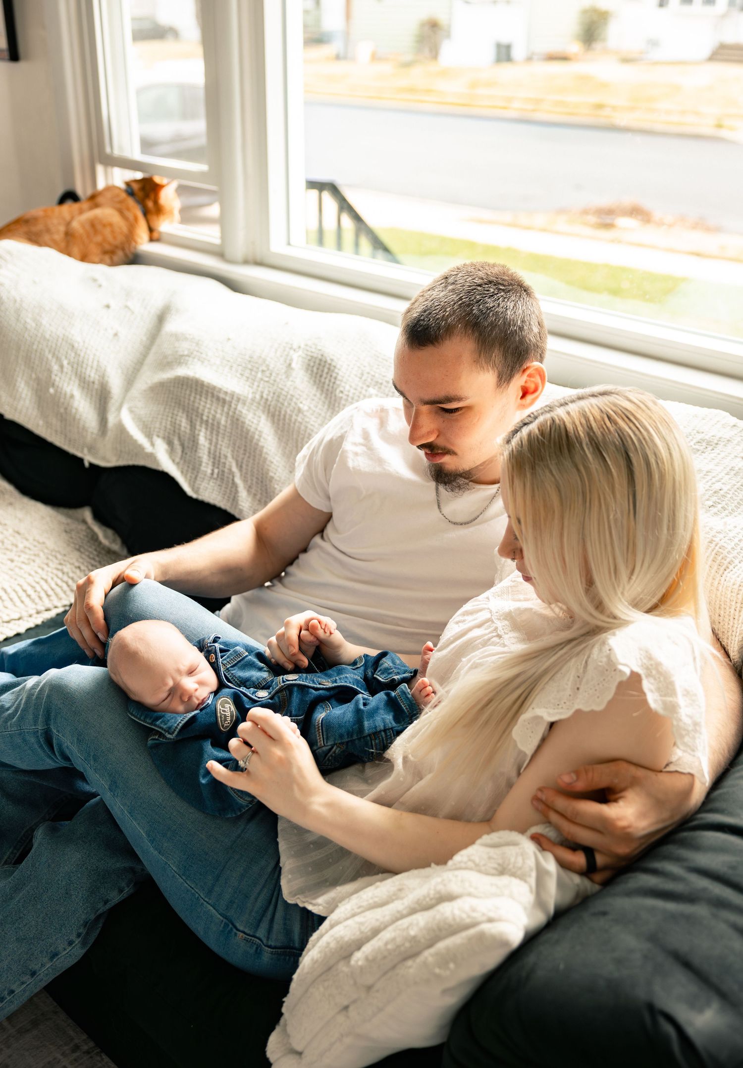 A couple relaxes together on a cozy window seat while sharing an intimate moment in natural light.